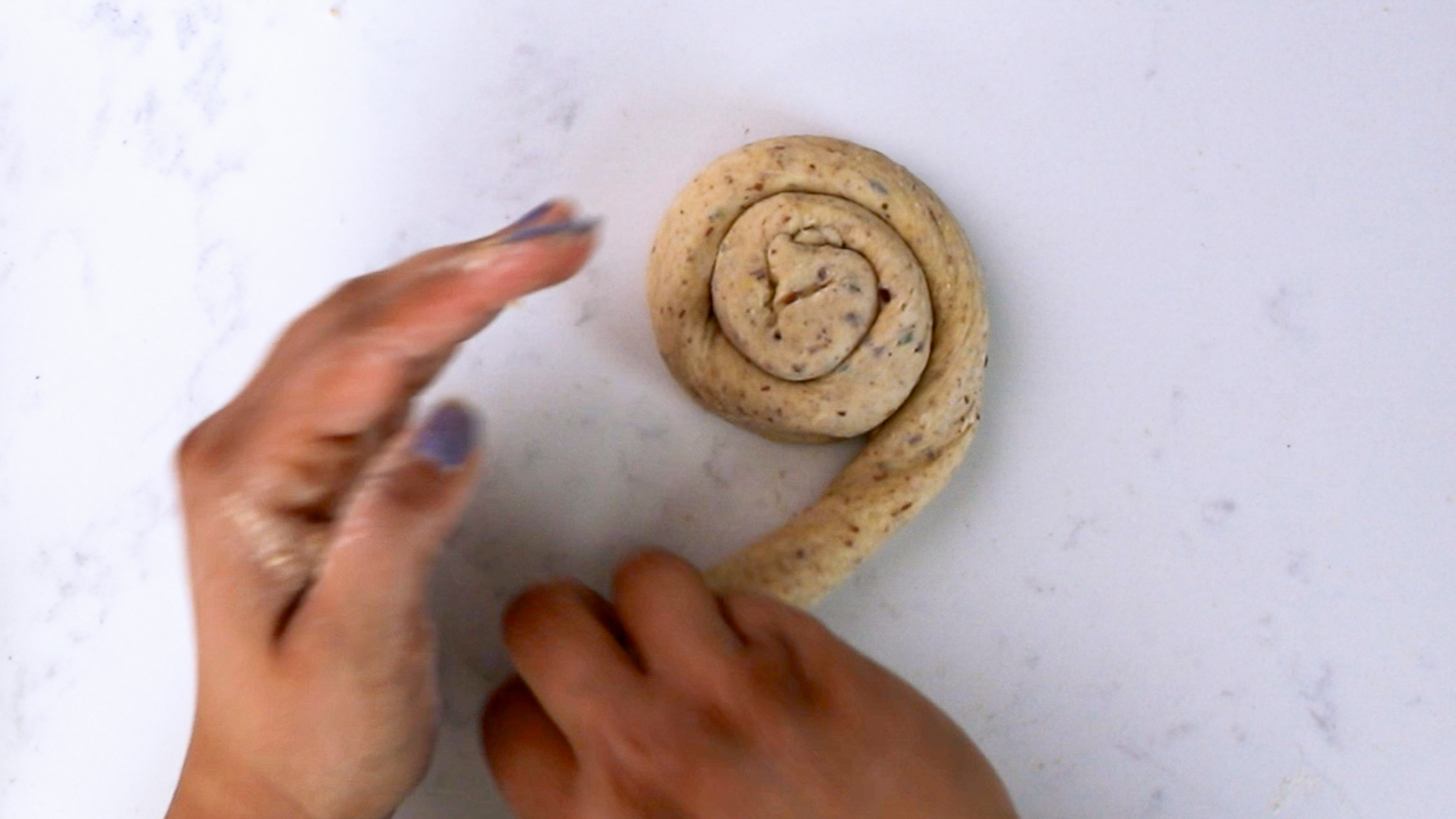 Hands finishing a swirl made of dough.