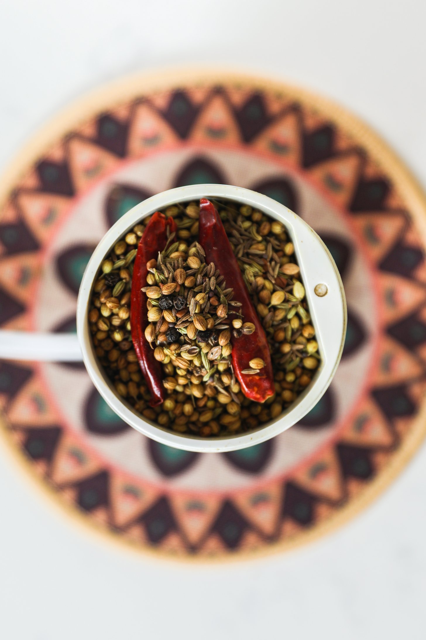 Top view of a coffee grinder with South Asian whole spices.
