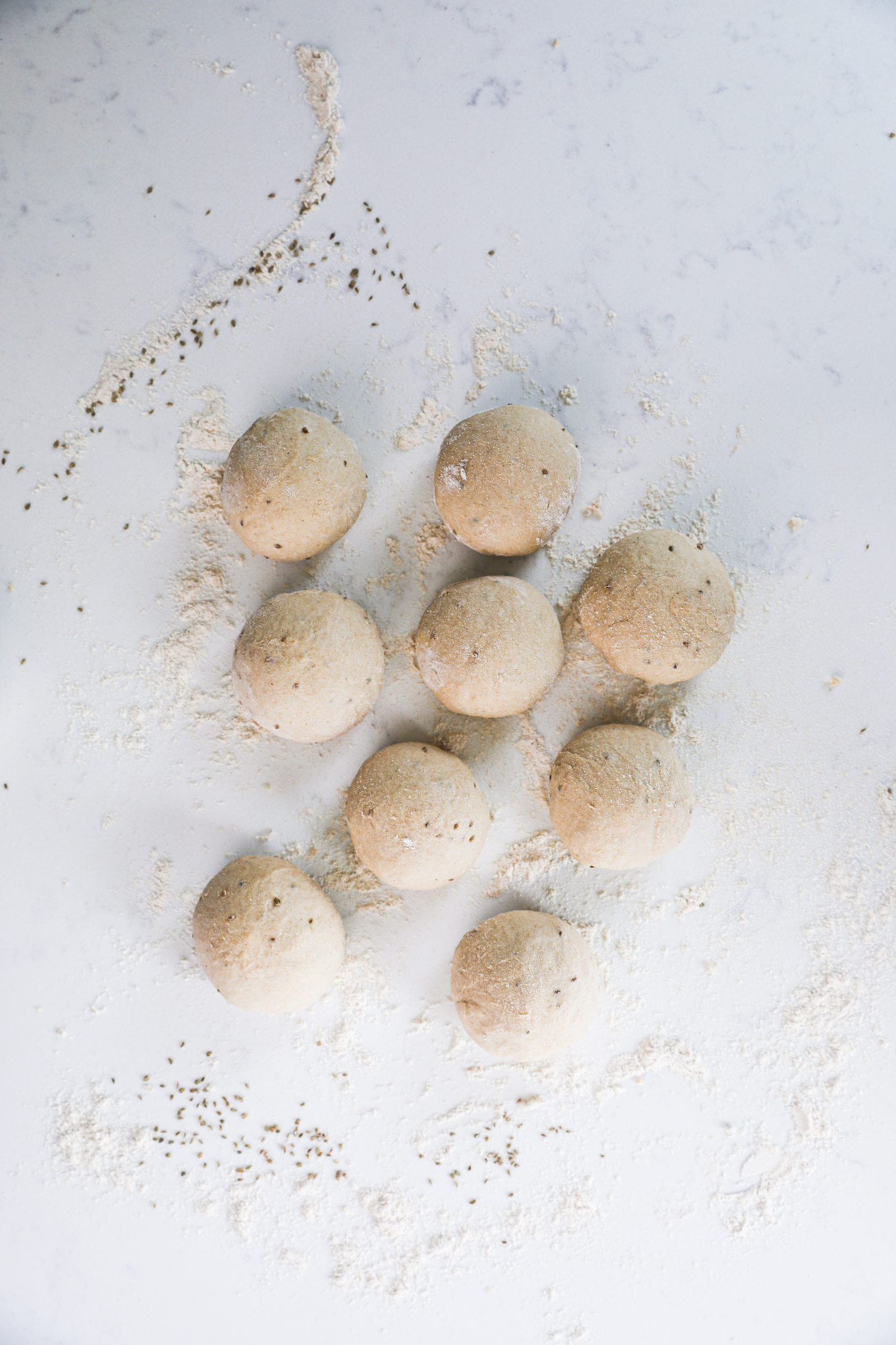 Eight balls of flour on a flour-dusted surface.