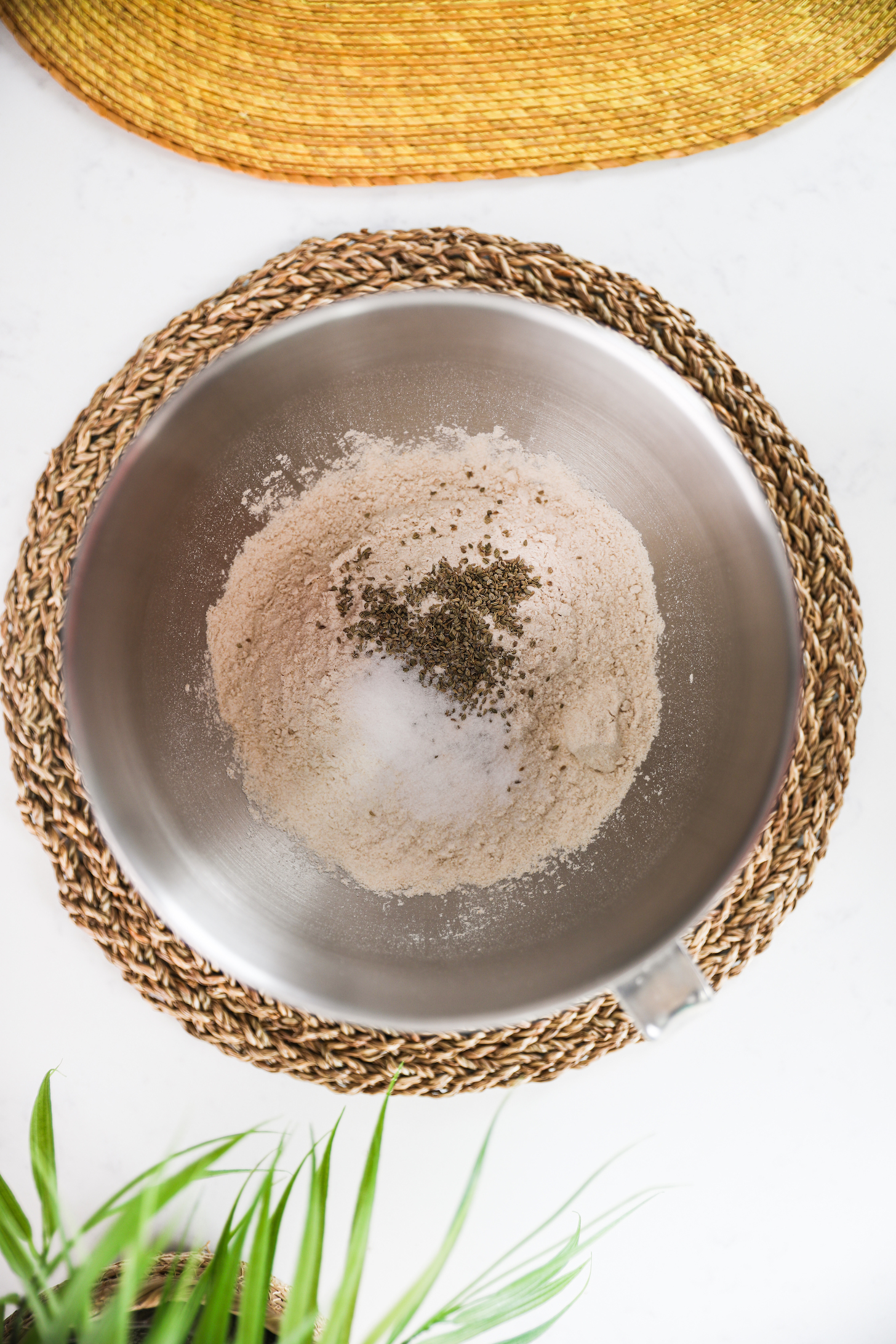 Flour topped with salt and seeds in a stand mixer bowl.