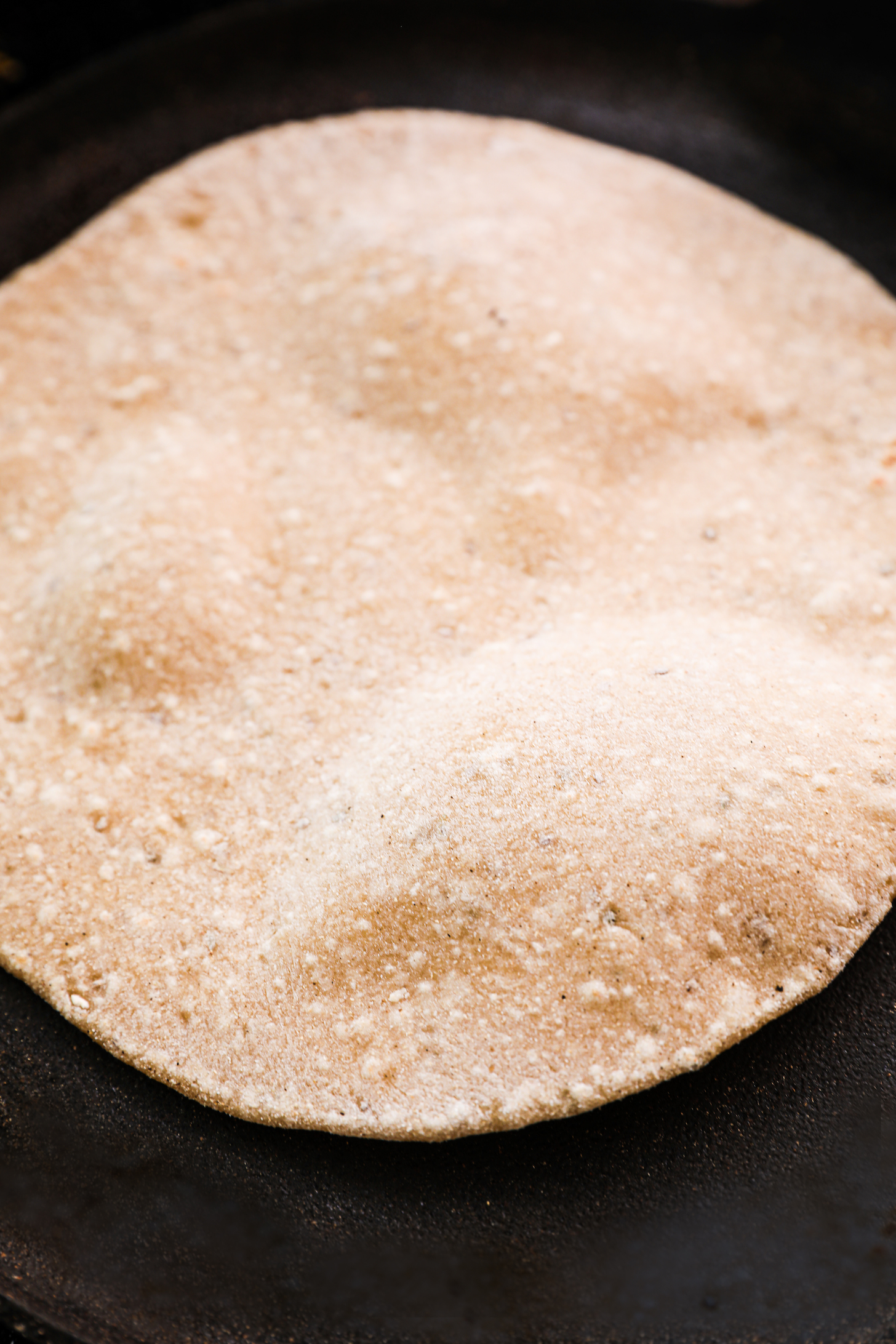 A roti puffing on a flat pan.