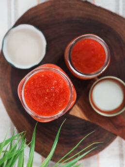 Overhead shot of 2 jars of tomato sauce on a wooden board.