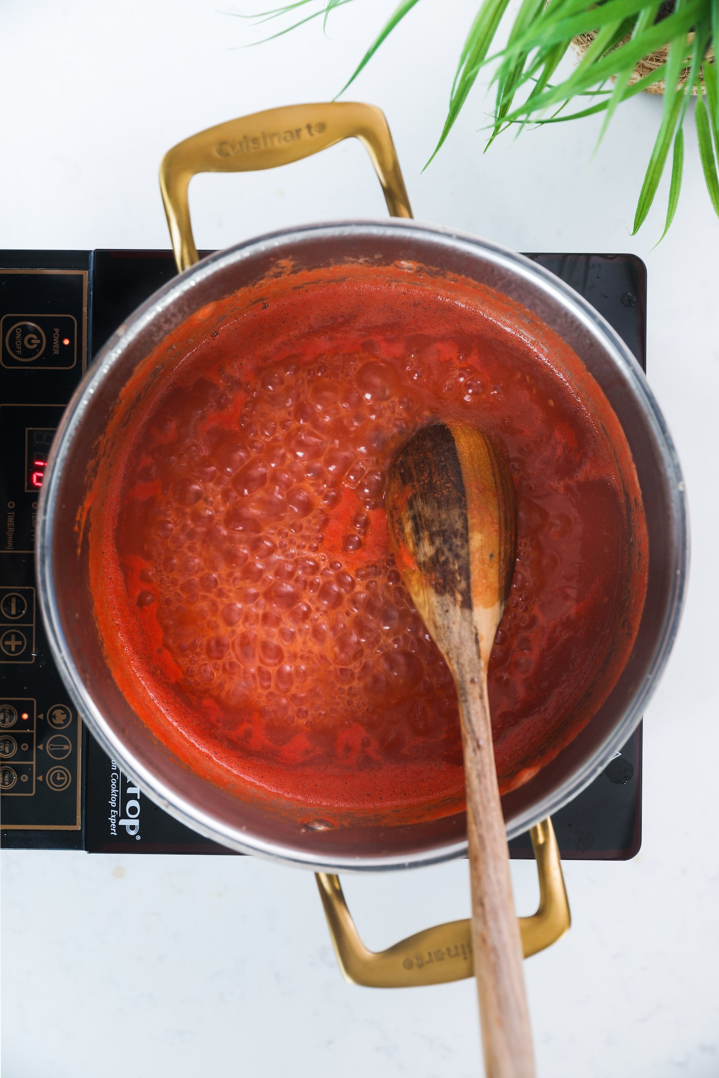 Bubbling tomato sauce in a pot with a wooden spoon.