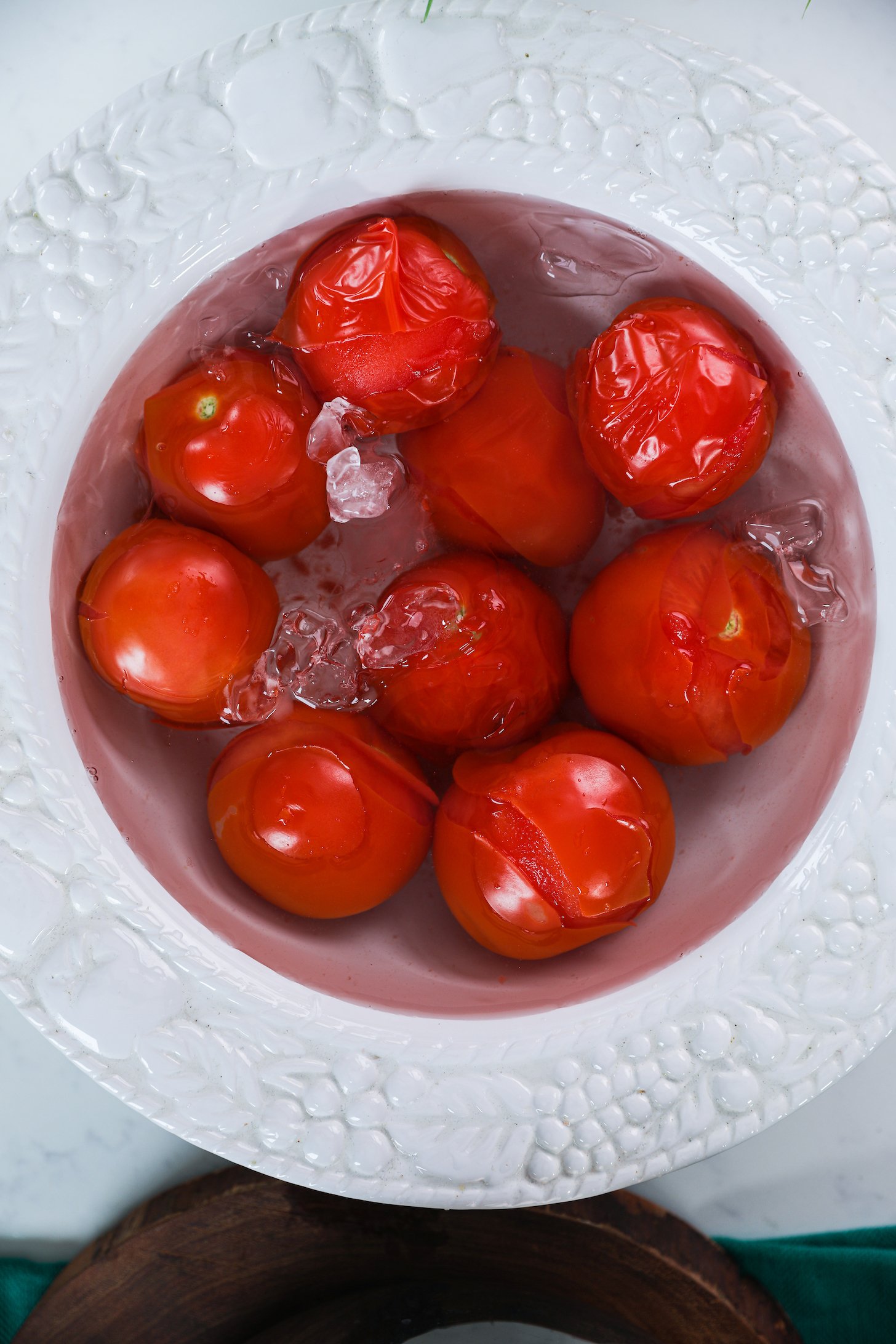 Wrinkled tomatoes submerged in a bowl of ice water.