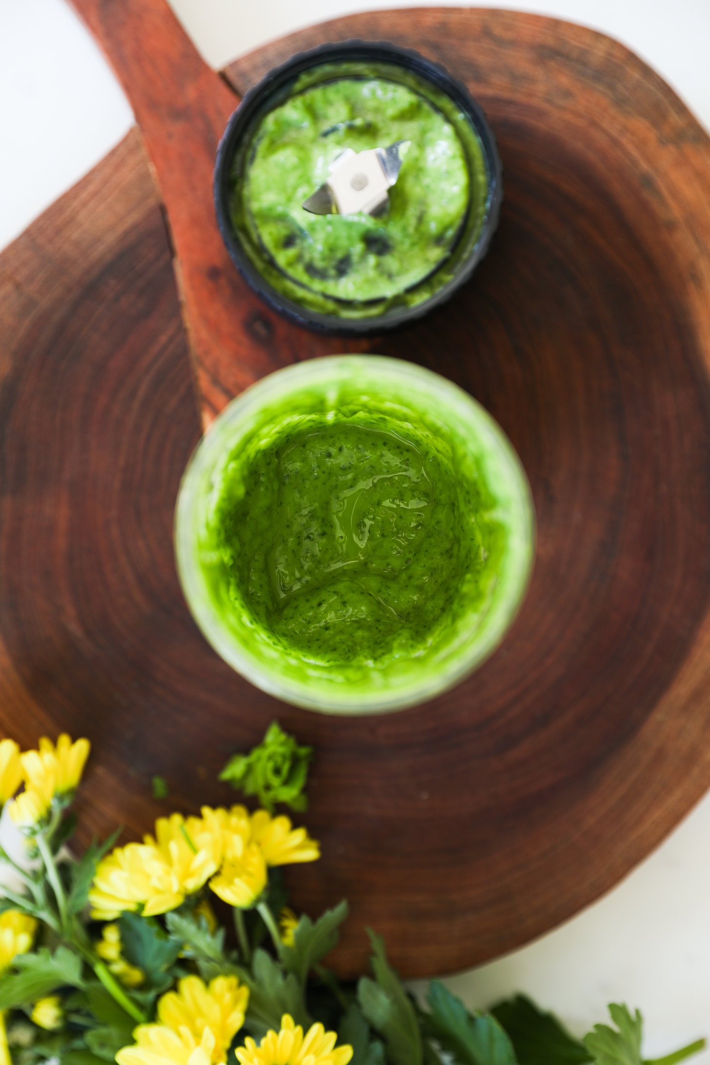 Top view of a small blender filled with an green dressing.