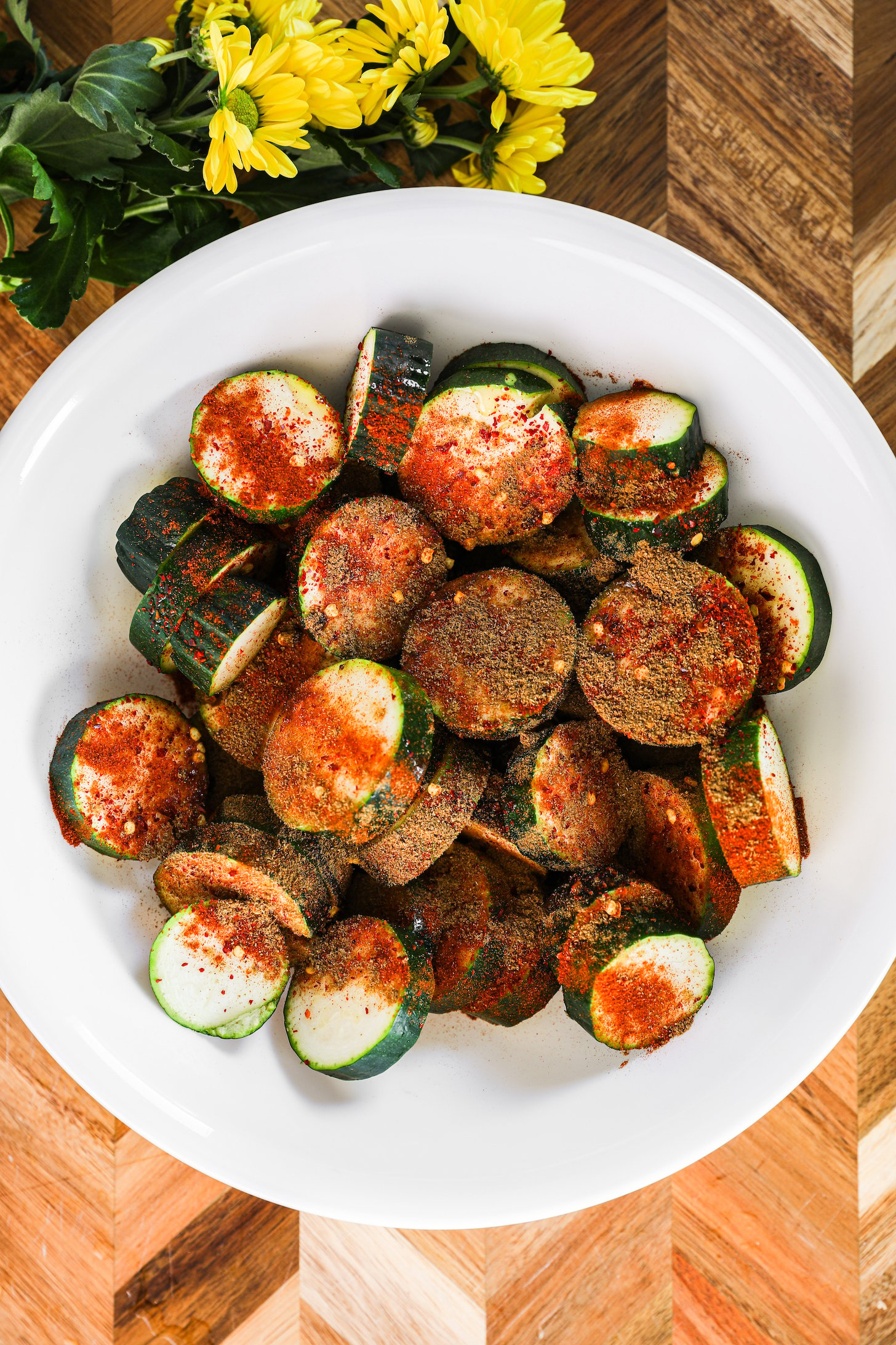 A bowl of zucchini rounds coated in powdered spices.