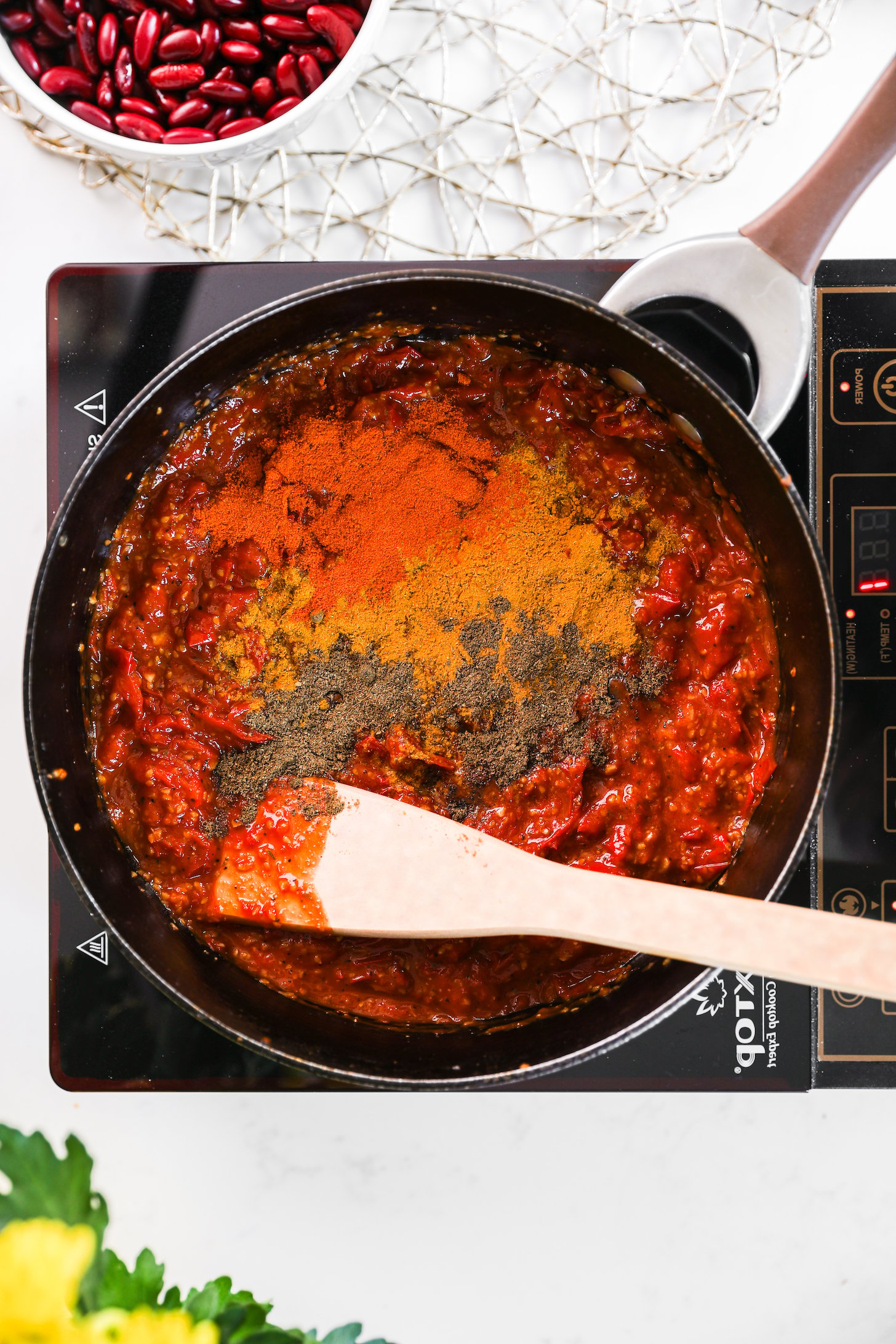 A pan of tomato sauce topped with colourful spice powders.