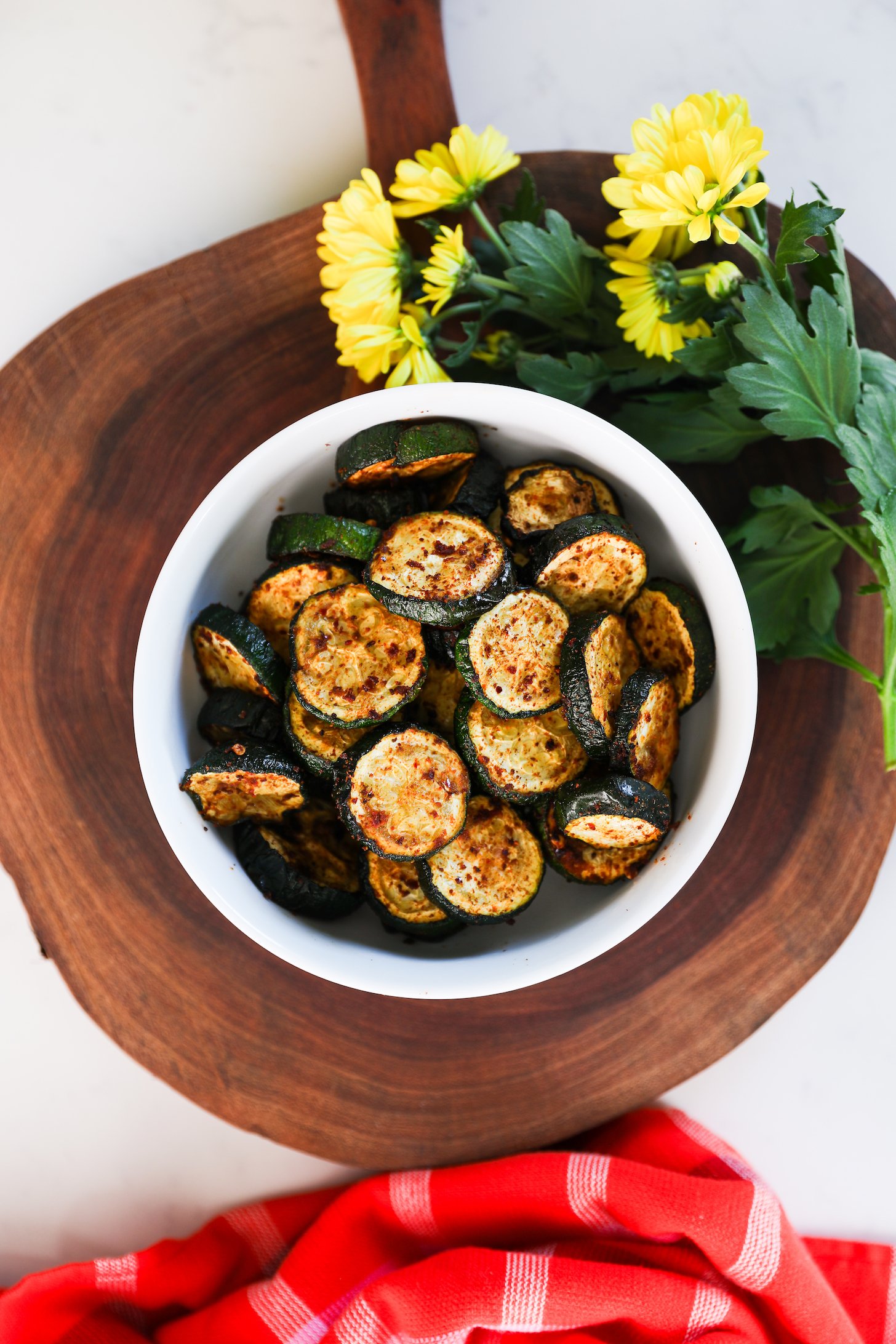 A bowl of charred zucchini on a wooden board.