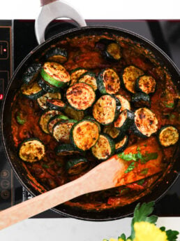 A pan of charred zucchini piled on top of tomato sauce.