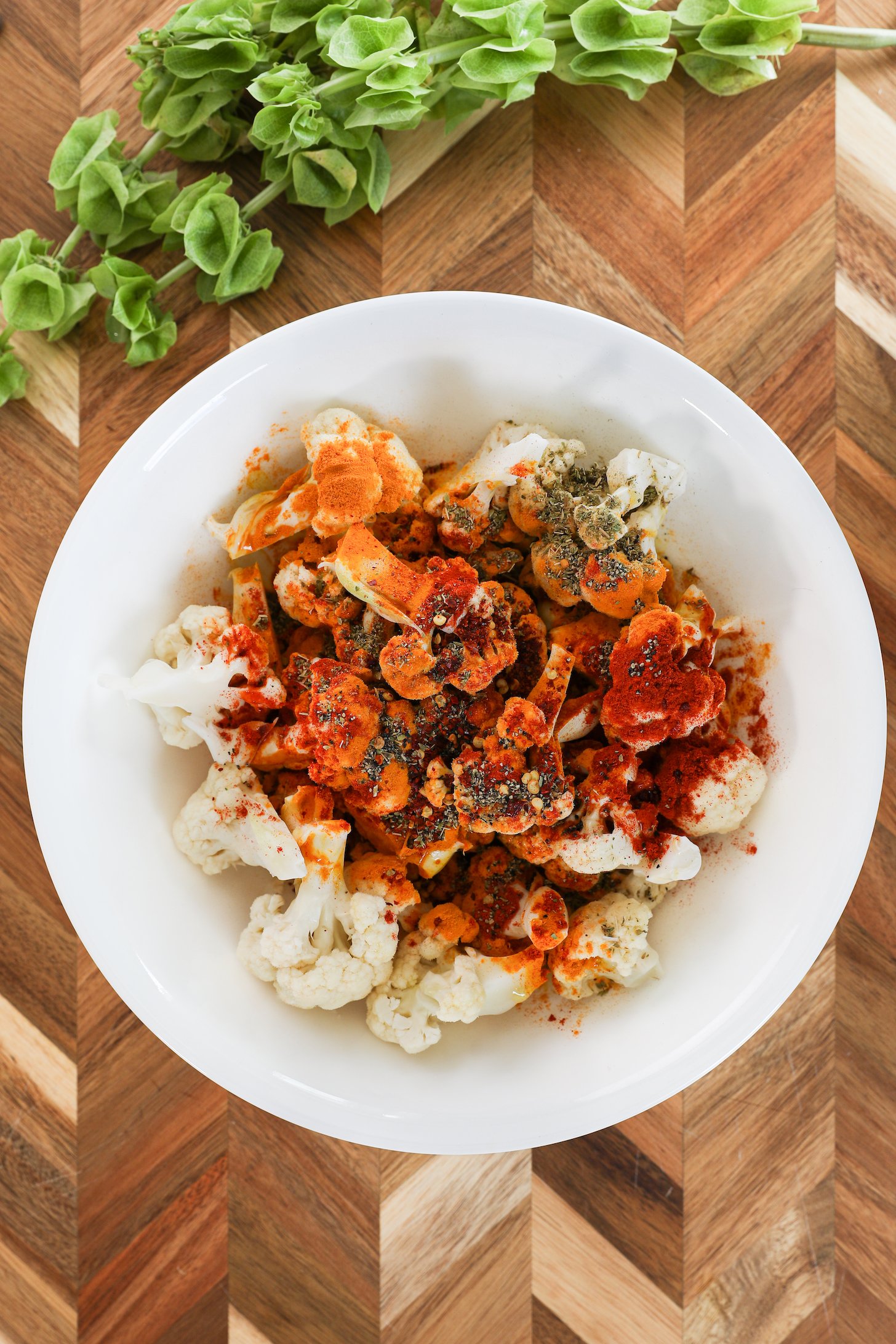 A bowl of cauliflower florets topped with colourful powdered spices.