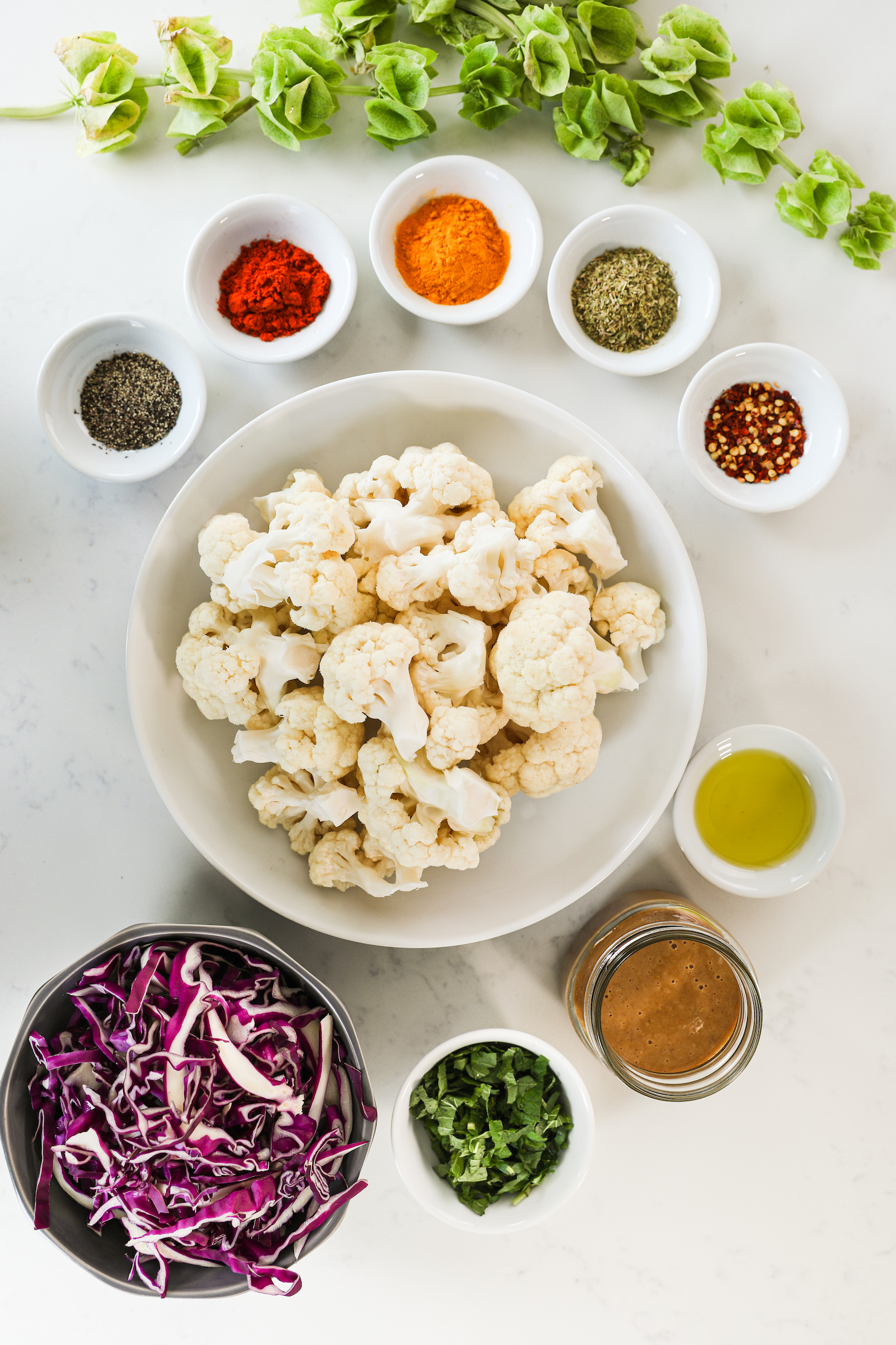 A selection of food ingredients like bowl of cauliflower and cabbage with different spices in ramekins.