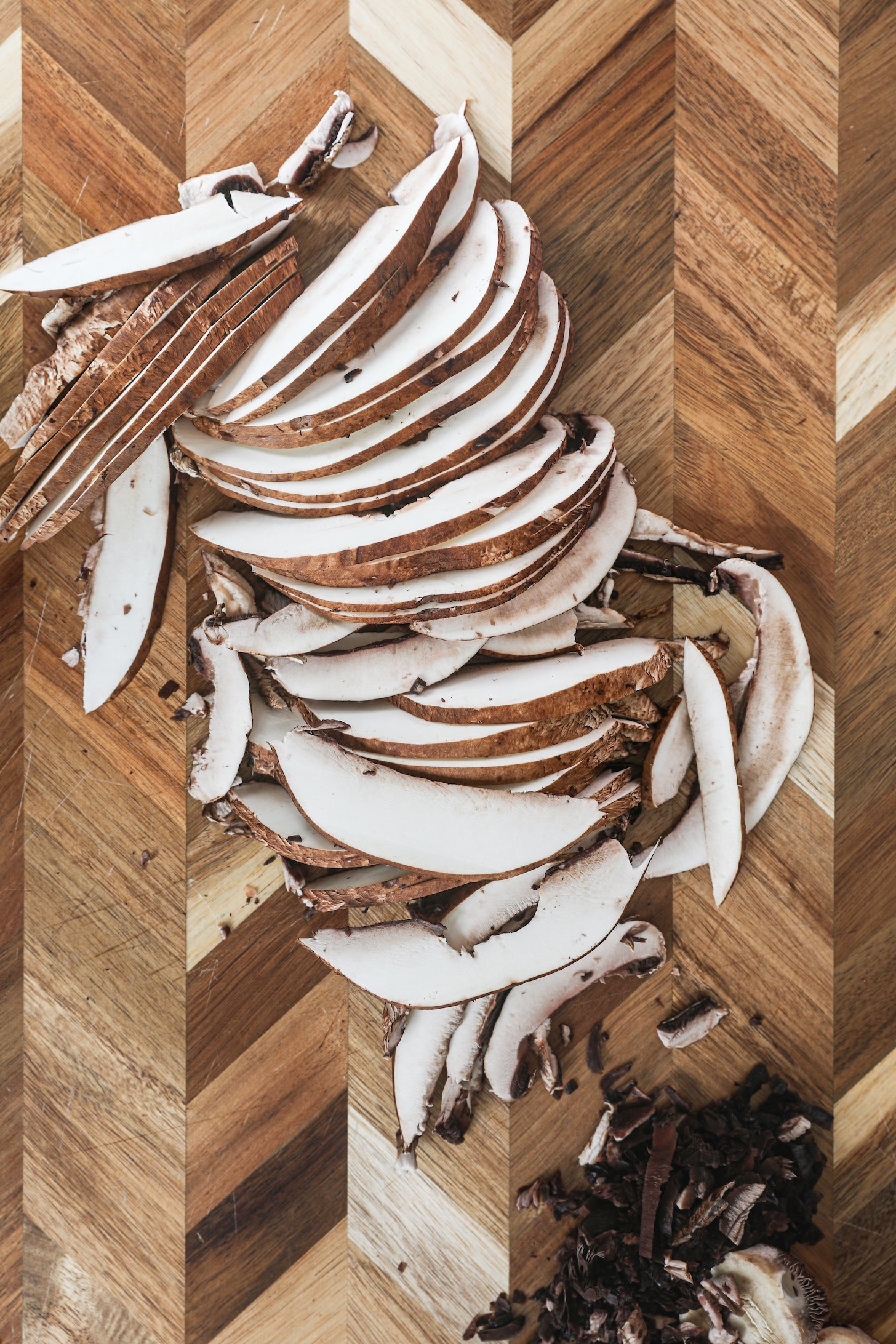Thinly sliced mushrooms on a wooden board.