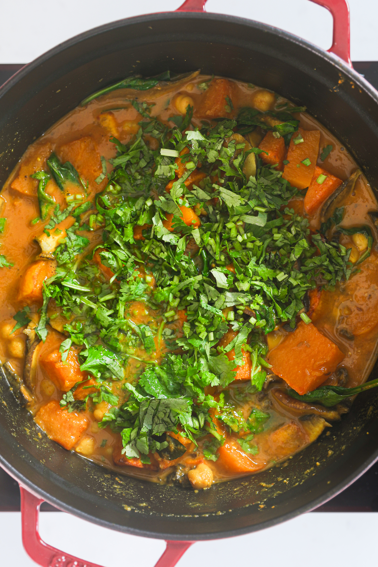 Butternut squash curry with chickpeas garnished with cilantro in a cooking pot.