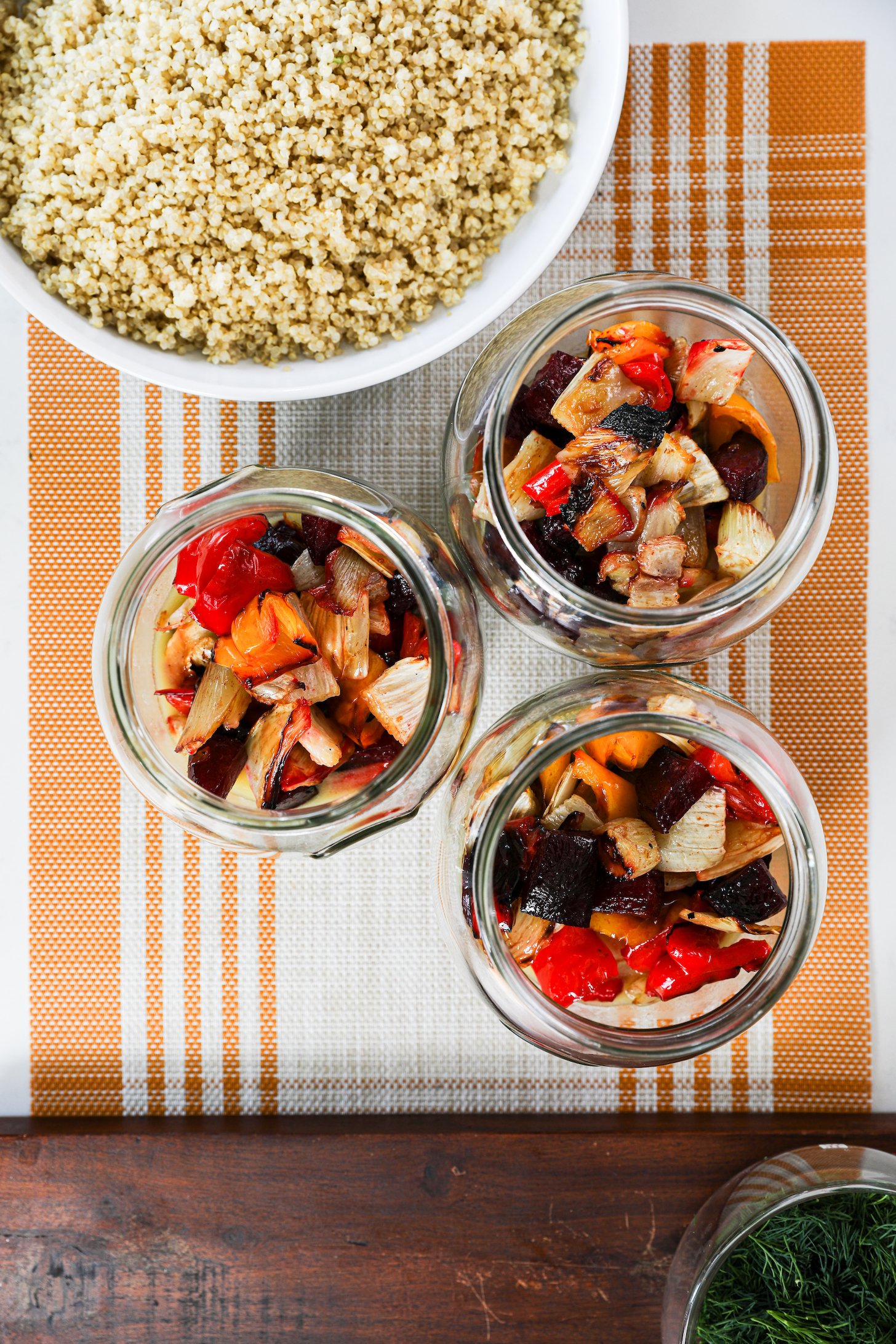 Three mason jars and a bowl of cooked quinoa placed nearby.