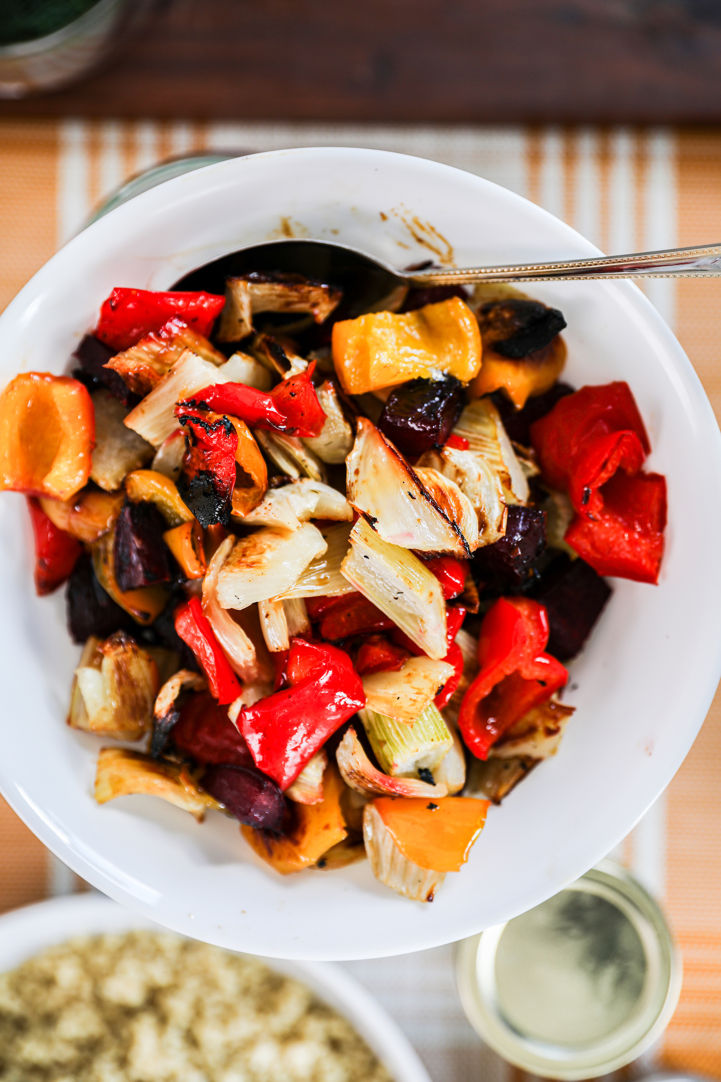 A bowl filled with oven-roasted vegetables, showcasing peppers, beets, and fennel.