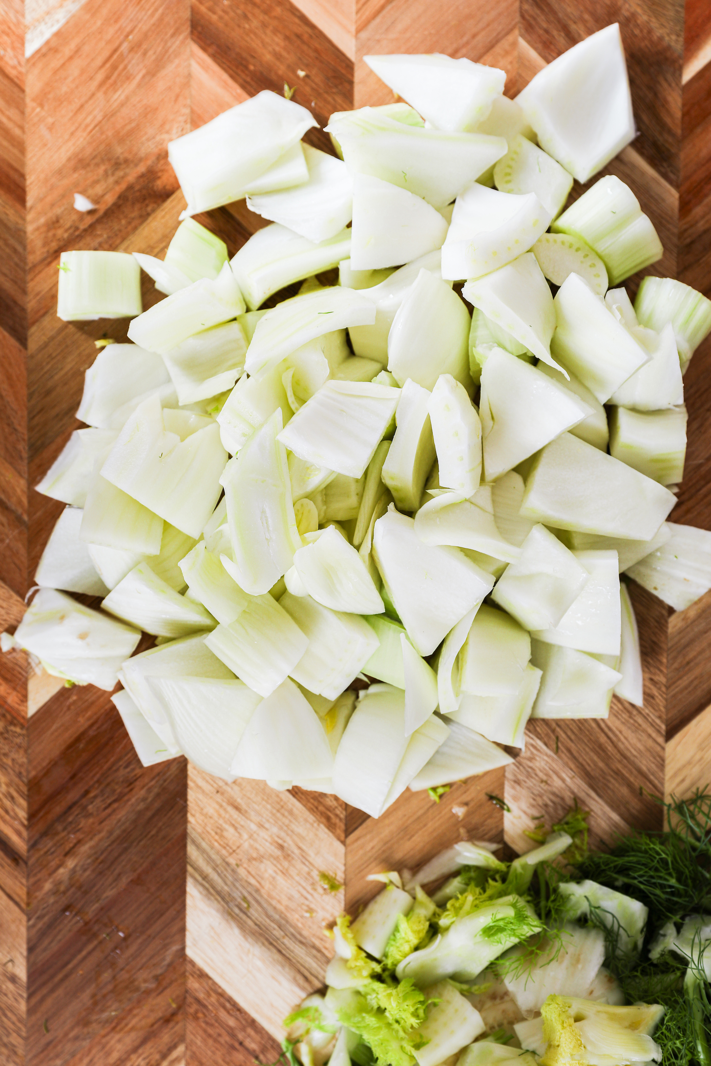 A mound of chopped fennel resting on a wooden chopping board, captured in detail for a visual experience.