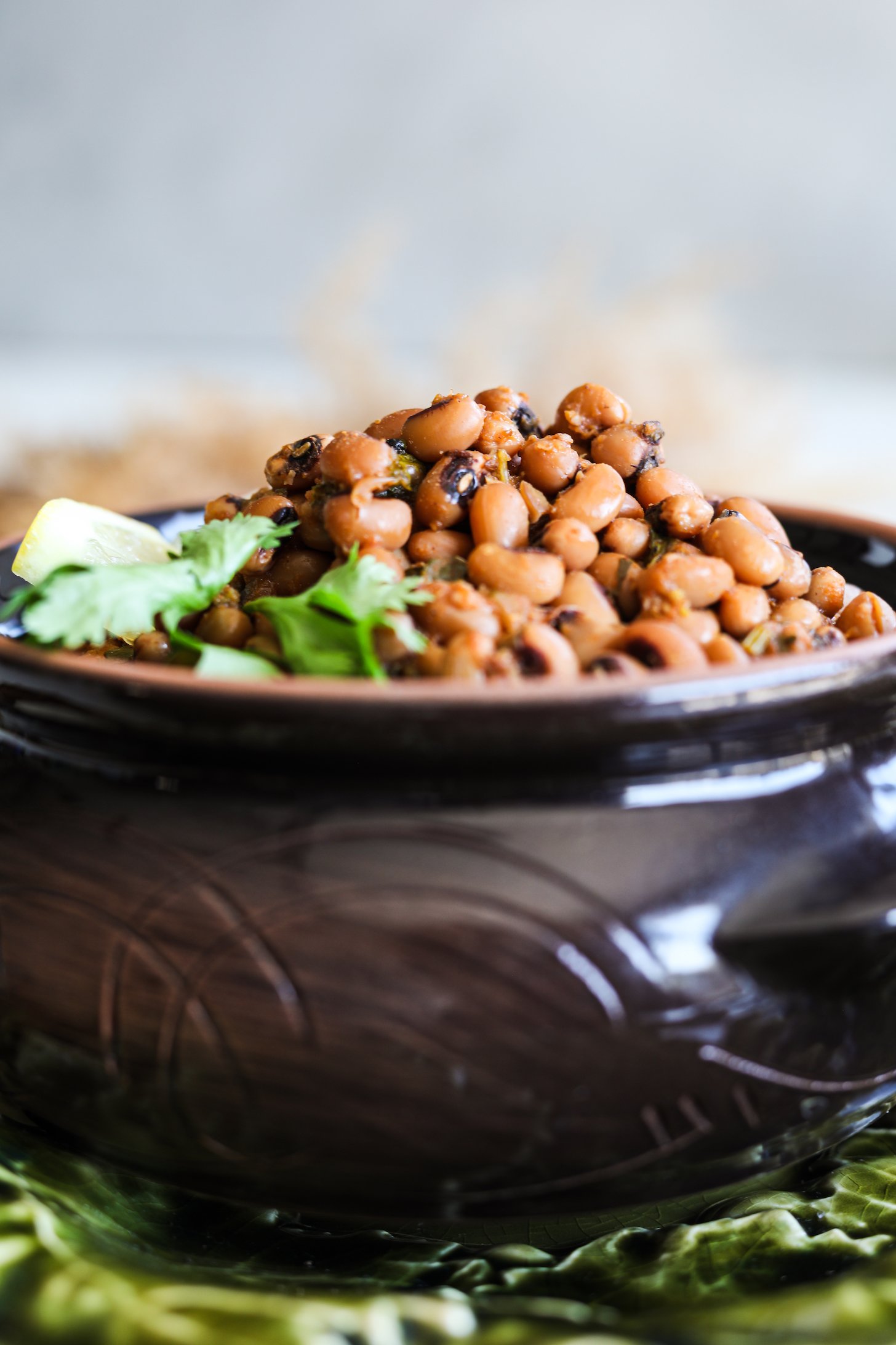 A clay serving pot filled to the brim with black eyed peas curry.