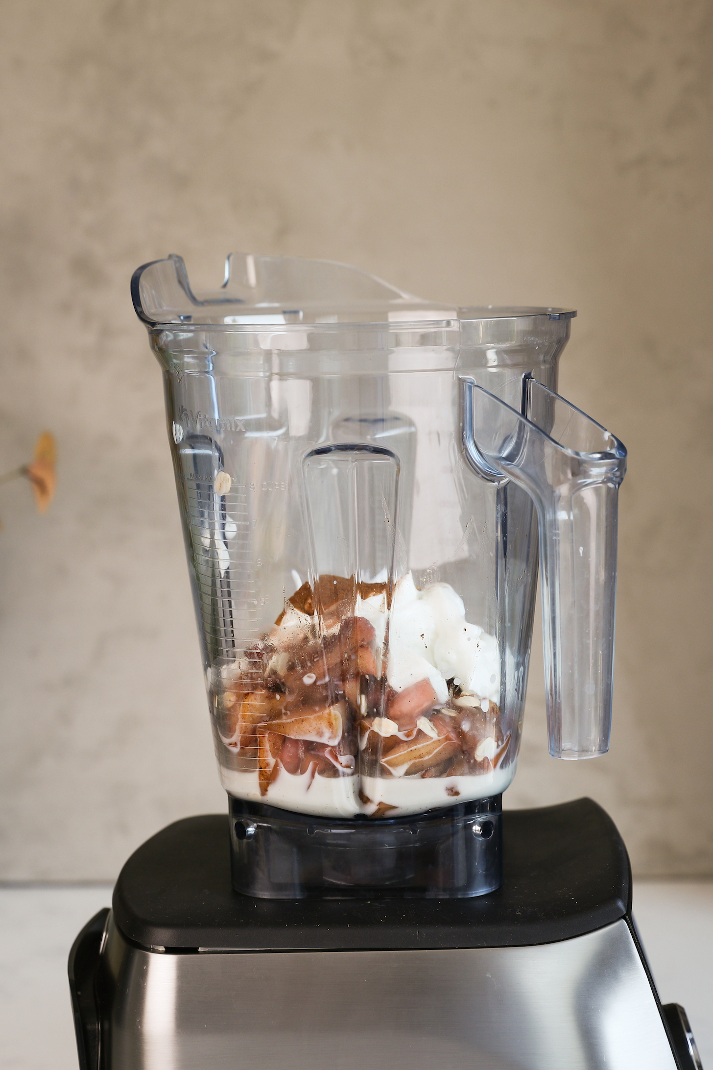 A blender with yogurt, milk, apple slices and spices.