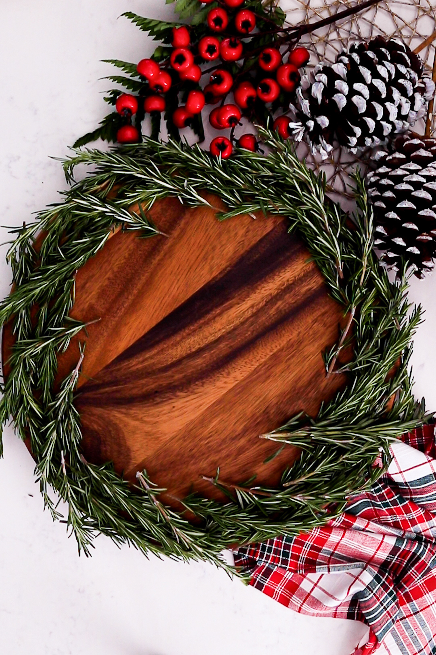 On a lazy Susan, a thick layer of fresh rosemary lines the edge, surrounded by festive decorations.