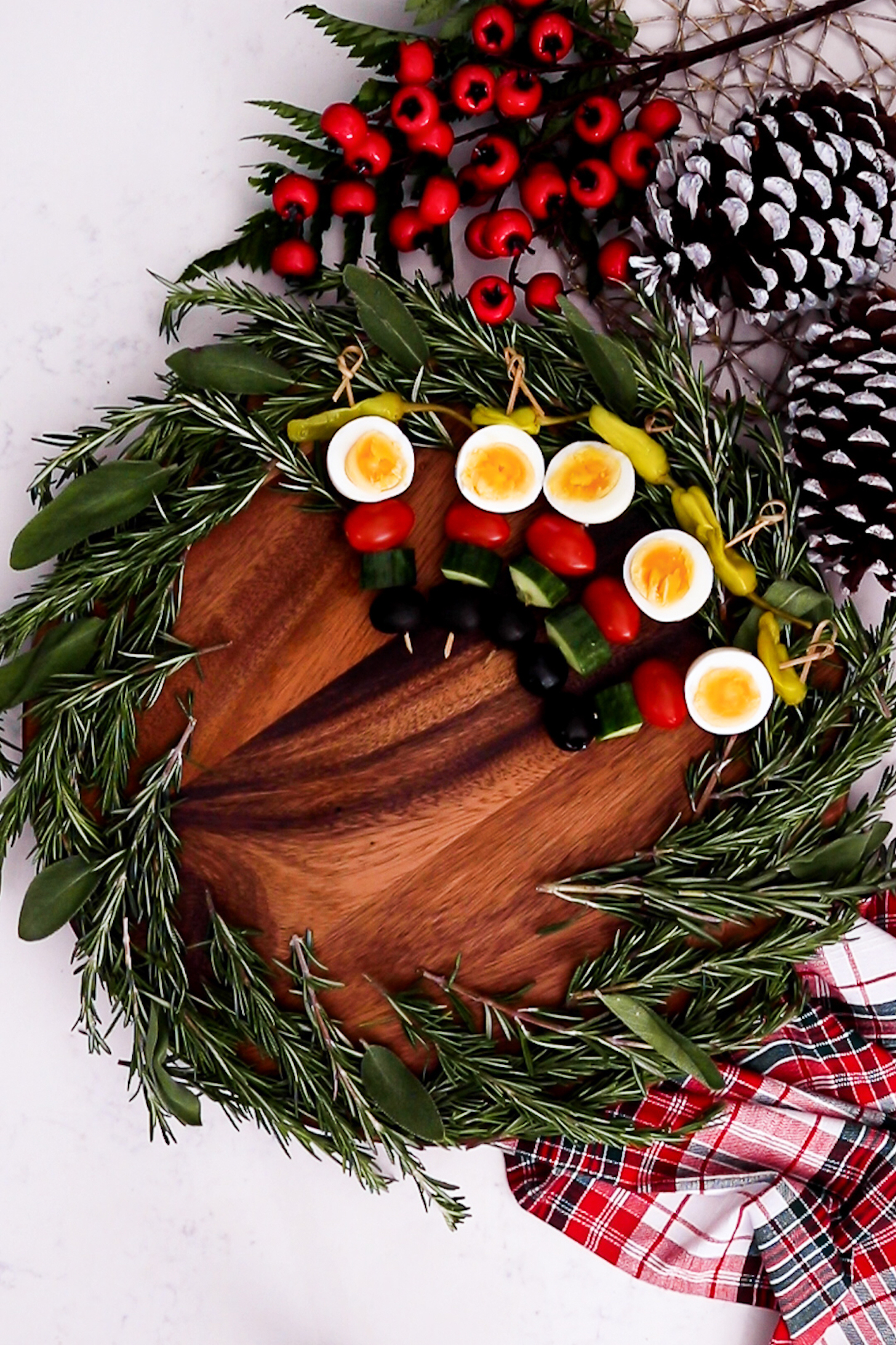 Creating a Christmas wreath: A lazy Susan hosts a thick layer of fresh rosemary and a few sage leaves encircling its edge, adorned with skewers featuring boiled eggs.