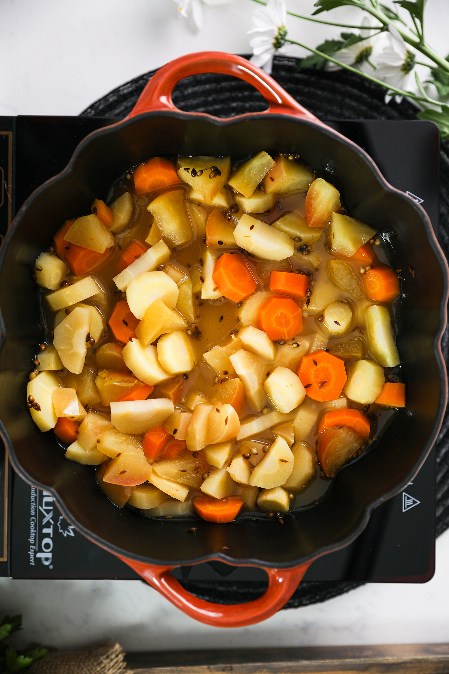 نمای بالای سر جعفری خرد شده، سیب و هویج موجود در داخل قابلمه پخت و پز.