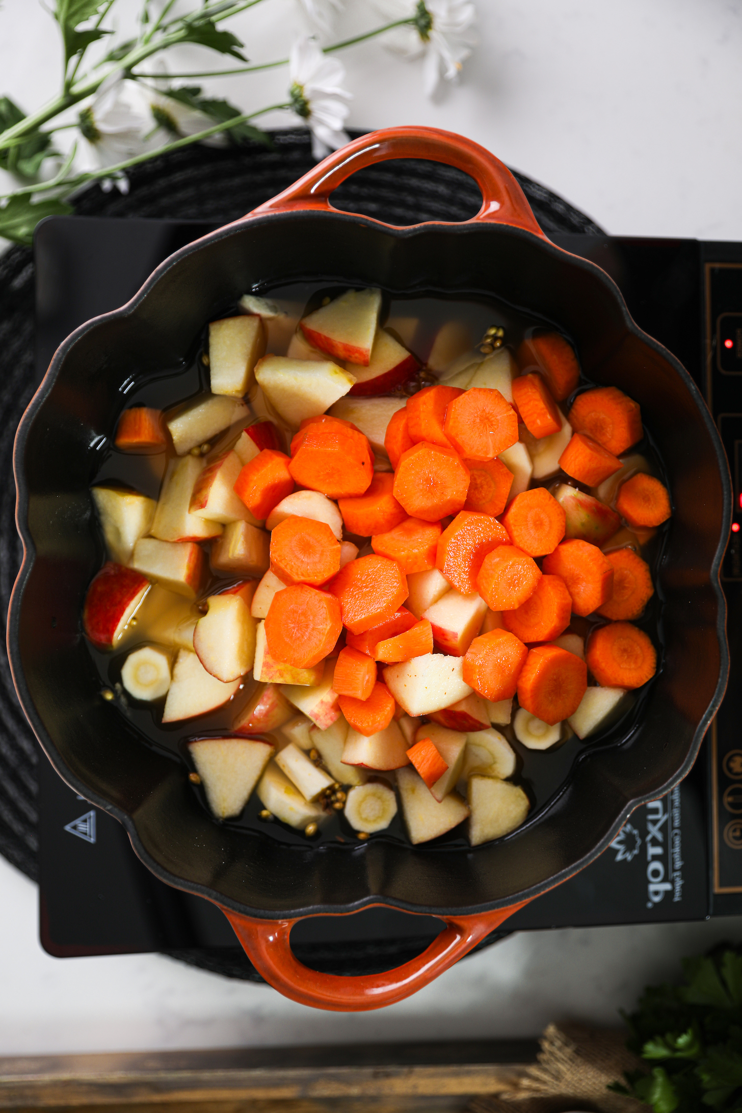 نمای بالای هویج، سیب و ازگیل خرد شده در داخل یک قابلمه پخت و پز.