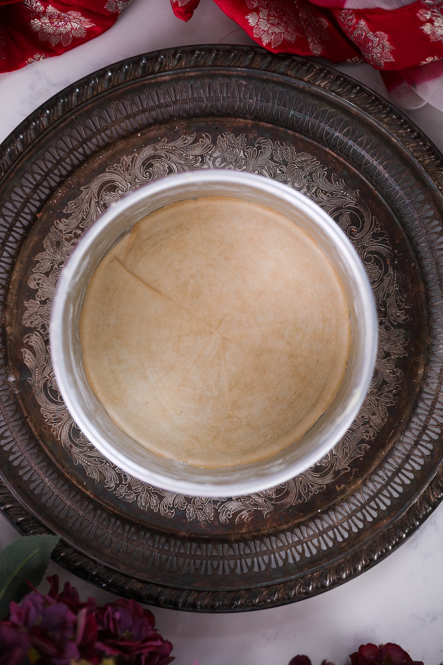 A round buttered cake pan on a round tray lined with parchment paper.