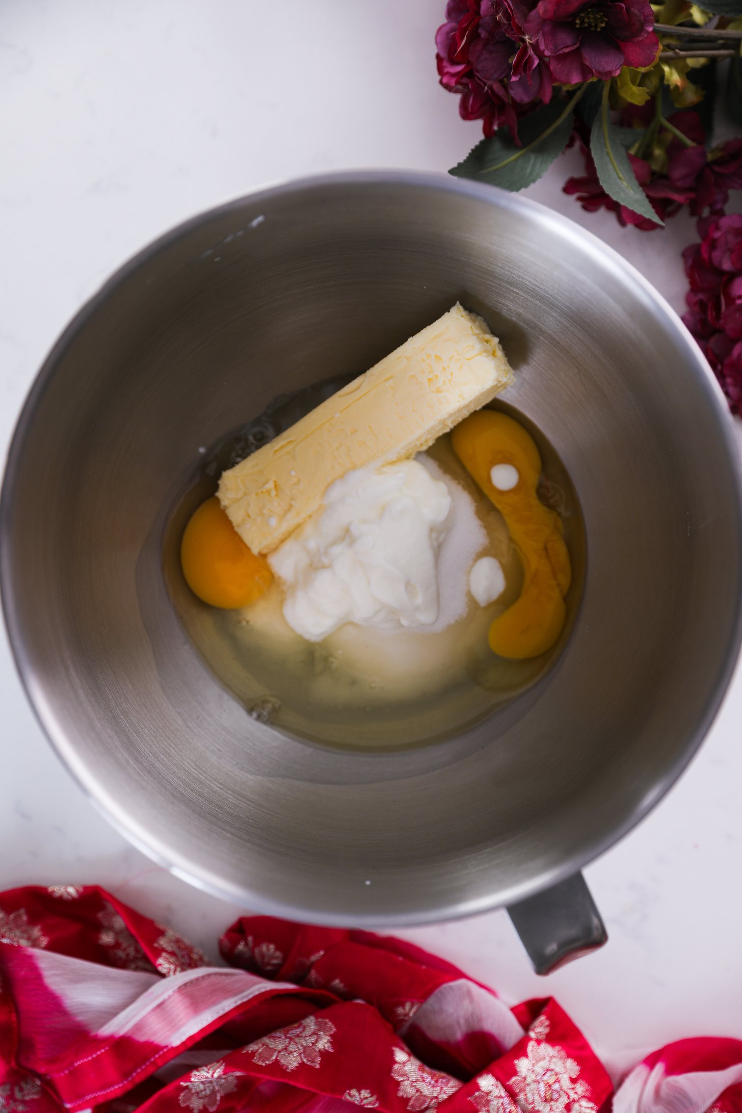 Overhead image of eggs, yogurt, butter and sugar in a stand mixer bowl.