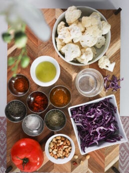 A selection of food ingredients including vegetables, spieces and oil on a wooden board.