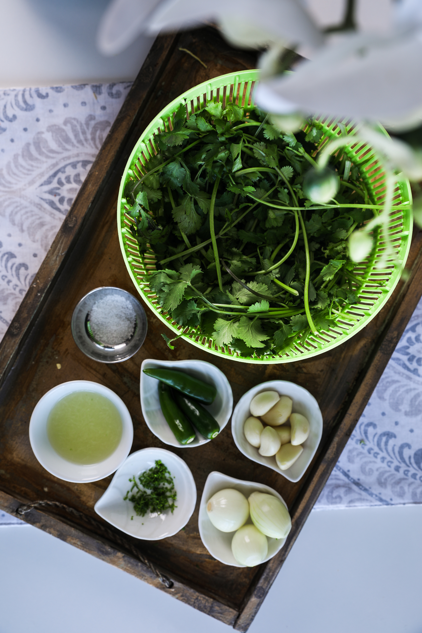 Overhead image of prepared food ingredients including cilantro, chillies, lime juice and zest, shallots and garlic cloves.