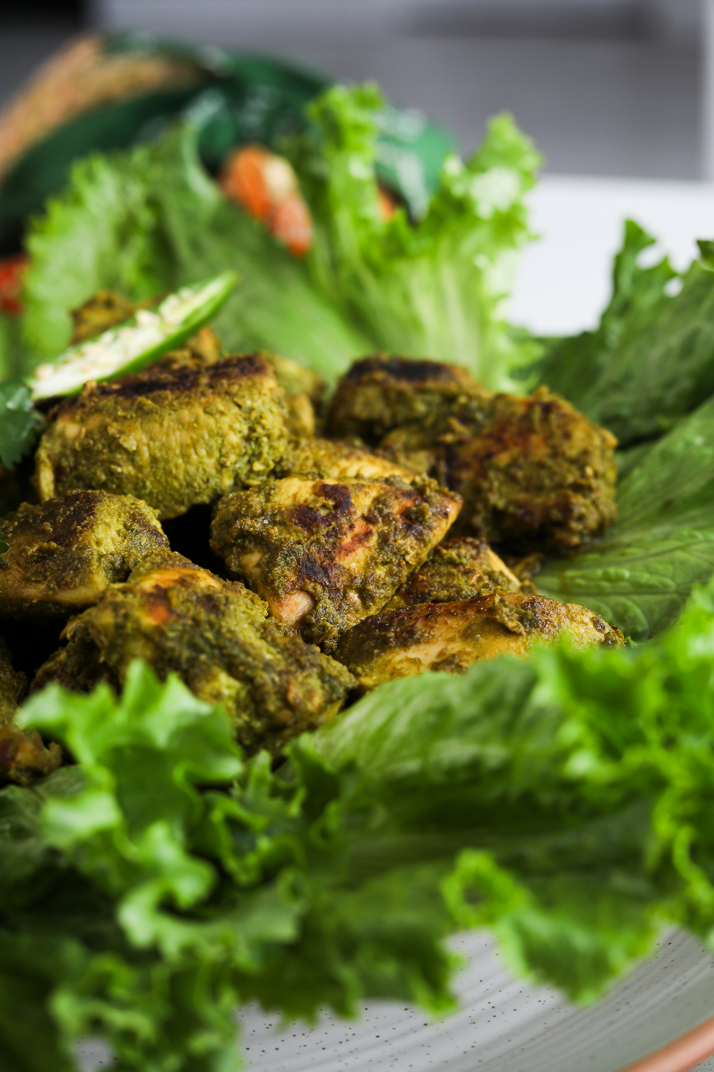 Perspective image of green chicken (Hariyali chicken) breast pieces placed on lettuce leaves.