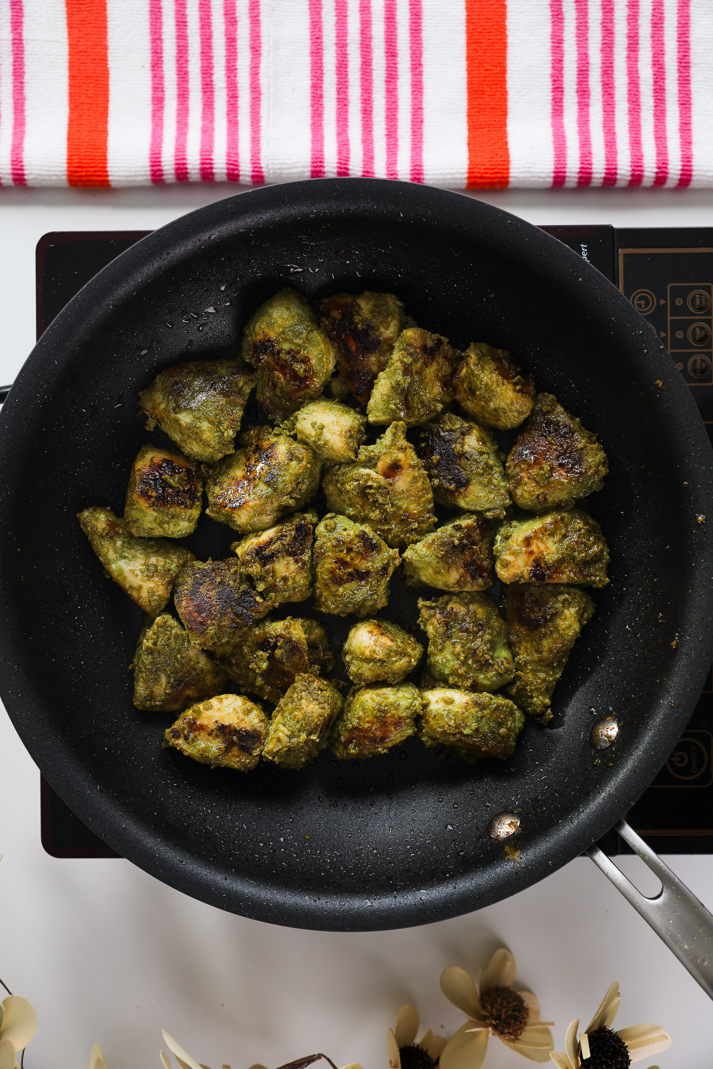 Pan of cooked and charred green masala-coated chicken breast pieces.