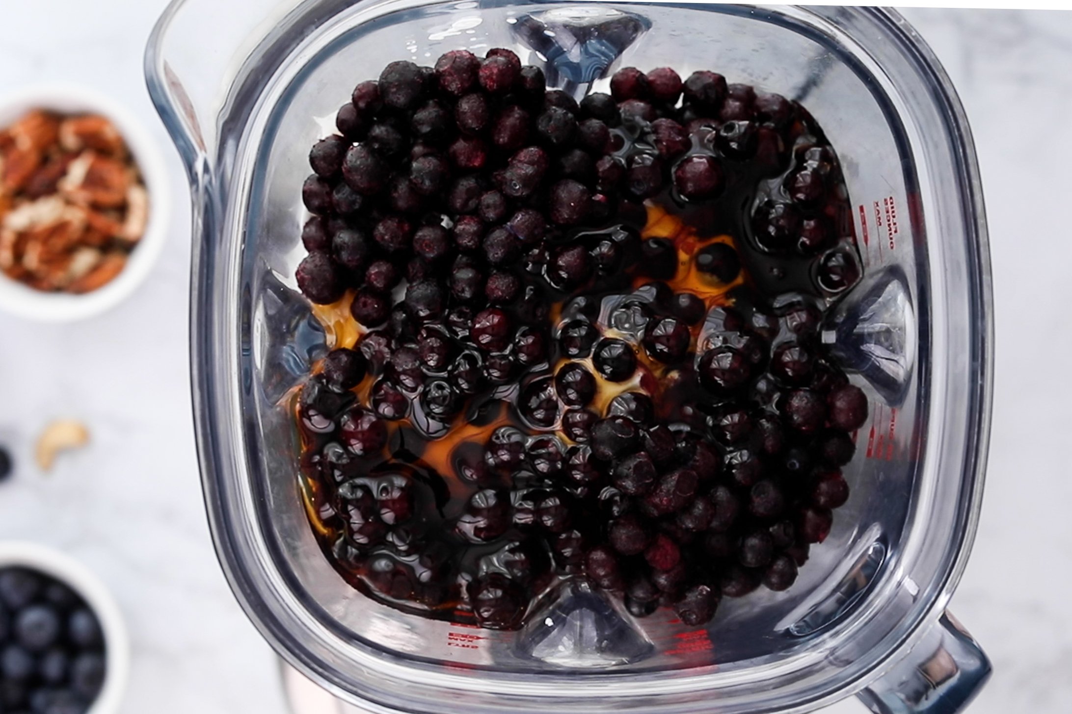 Top-down view of a blender brimming with berries and maple syrup.