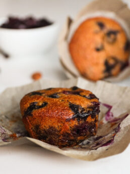 Close-up image of a blueberry muffin sitting on its liner.