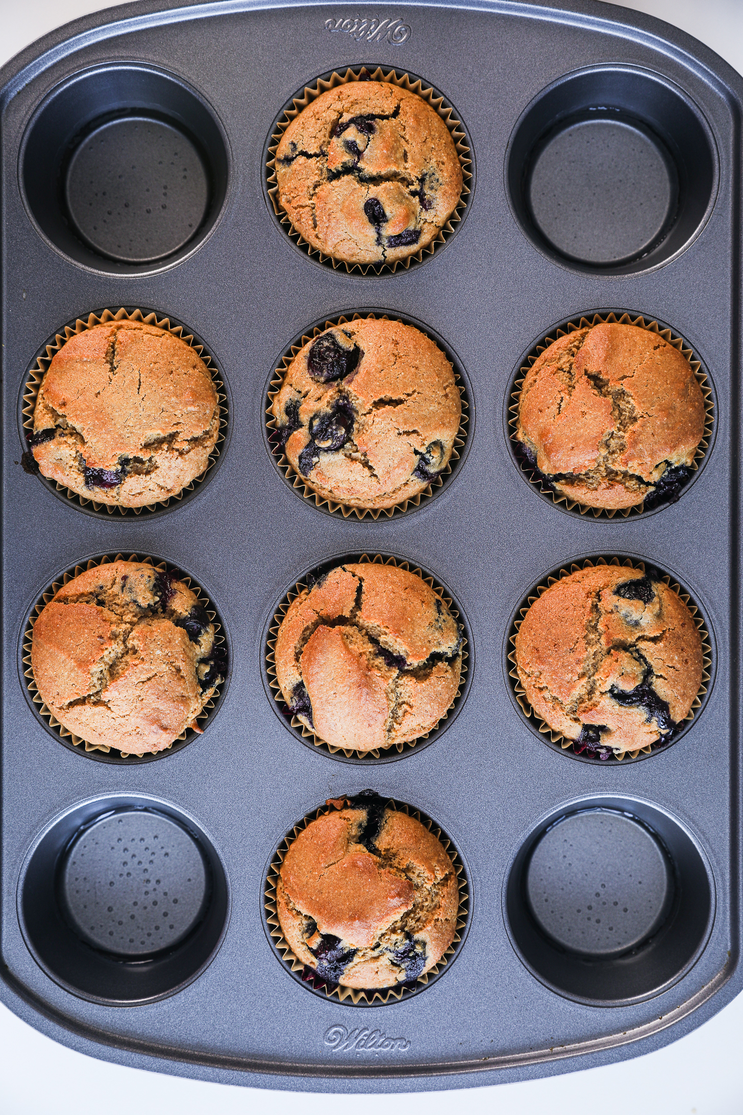 A cup cake tray with baked blueberry muffins.