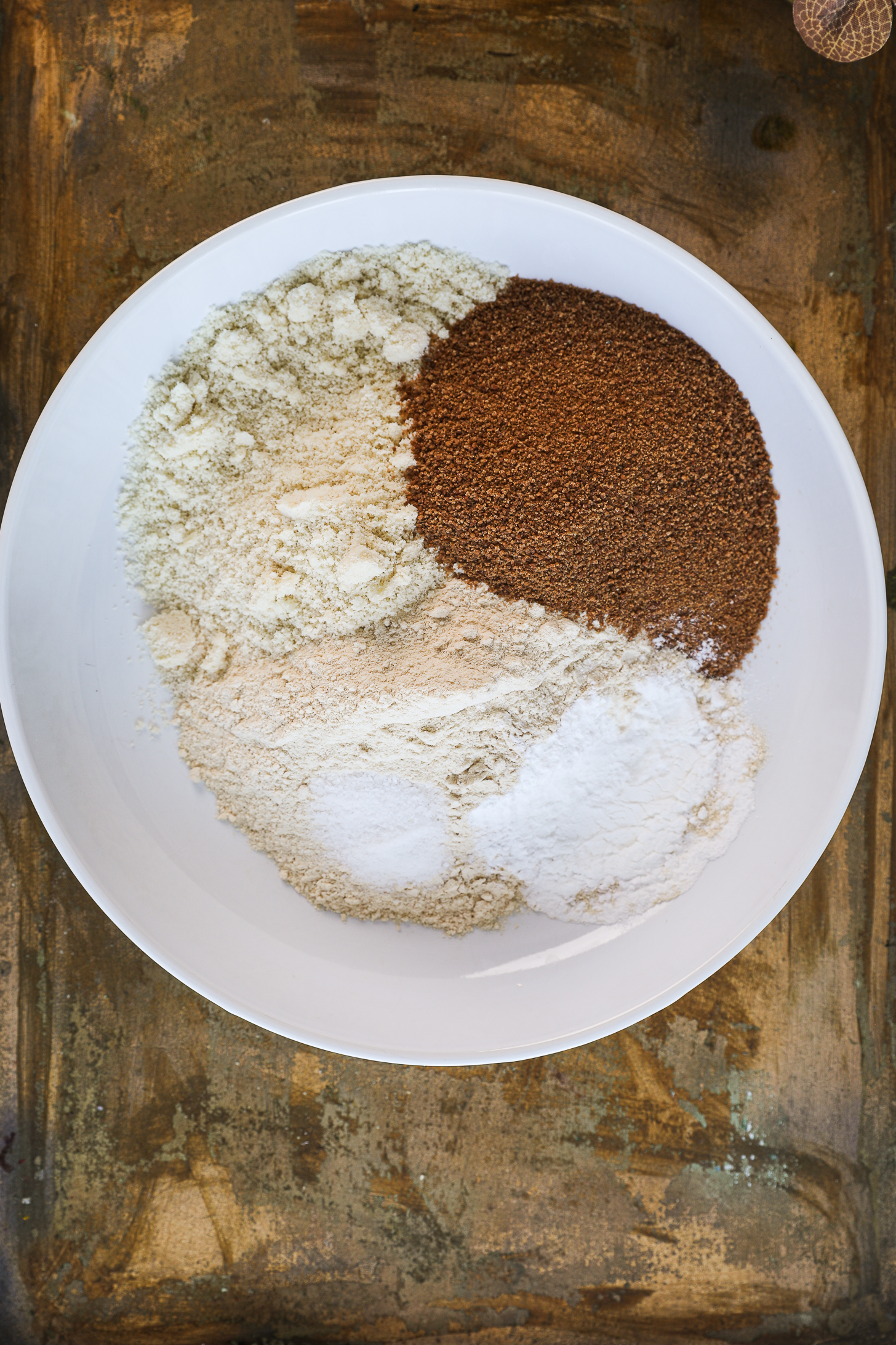 A bowl containing separate sections of various flours, coconut sugar, and baking powder.