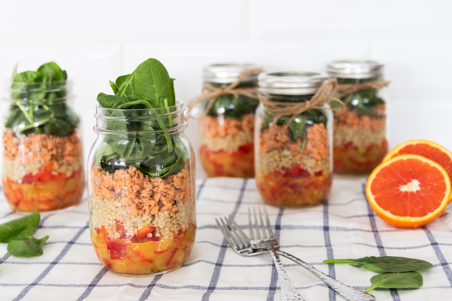 Vibrant mason jar salads layered with veggies, salmon, and greens.