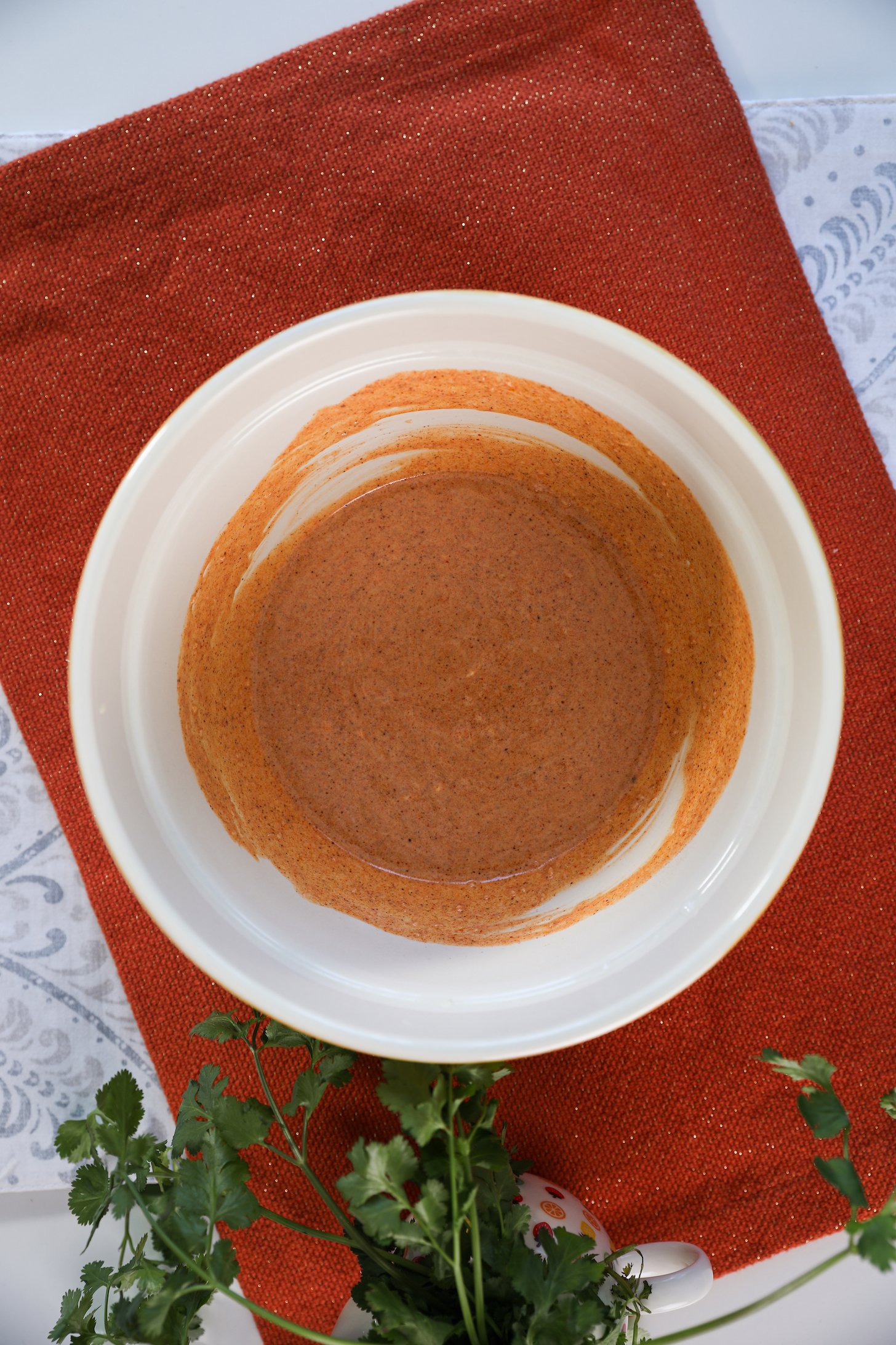 A bowl containing an orange marinade sits on an orange mat.