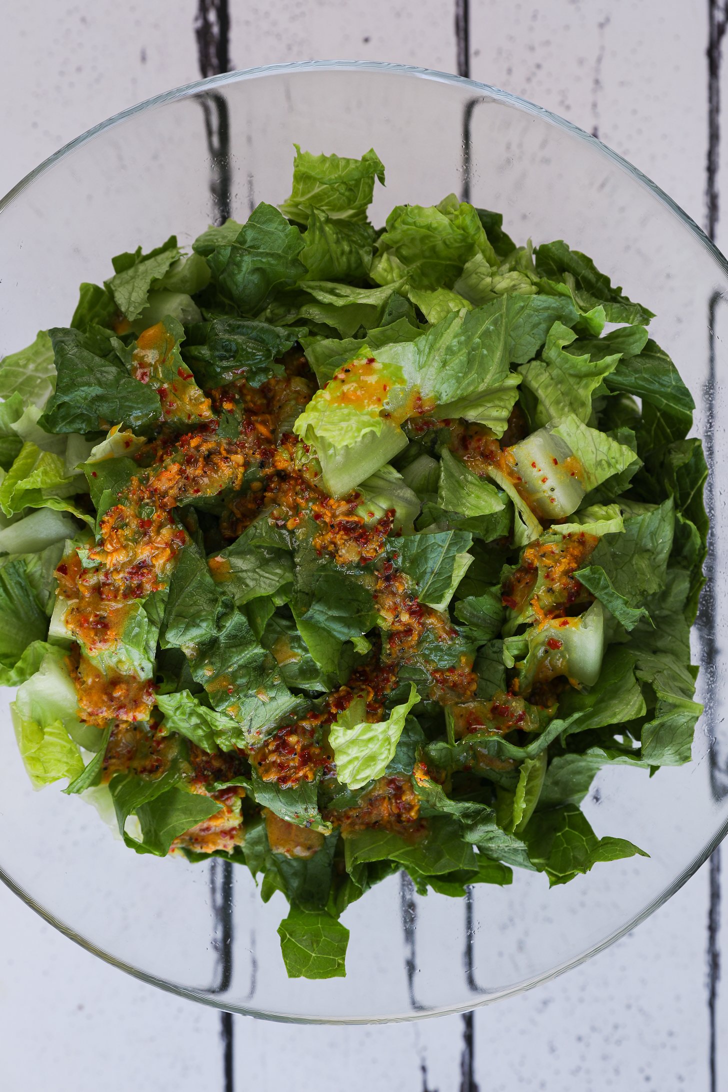 Top-view image of a bowl of chopped lettuce topped with a fresh turmeric salad dressing.