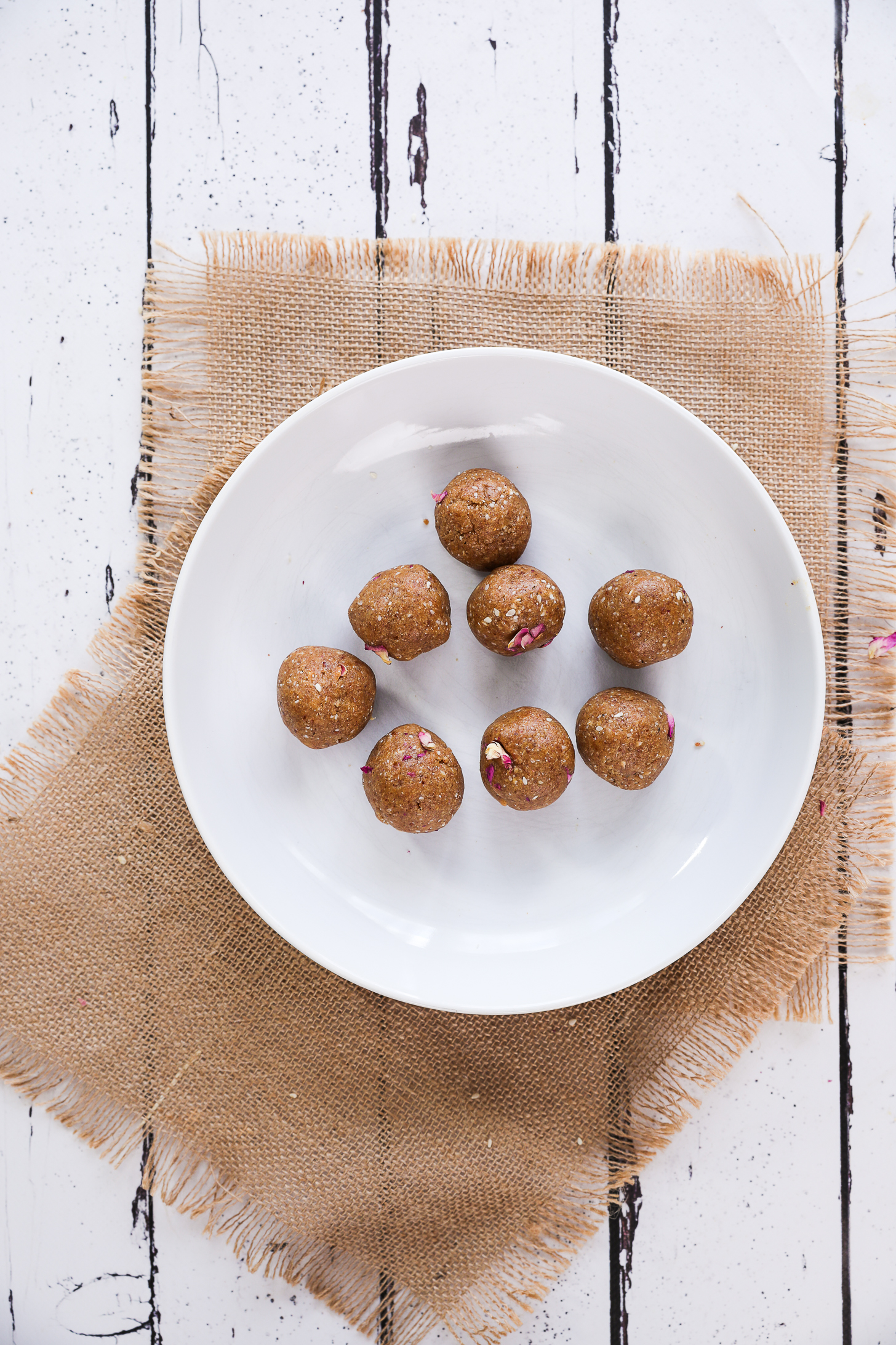 Eight brown bliss balls in a white plate.