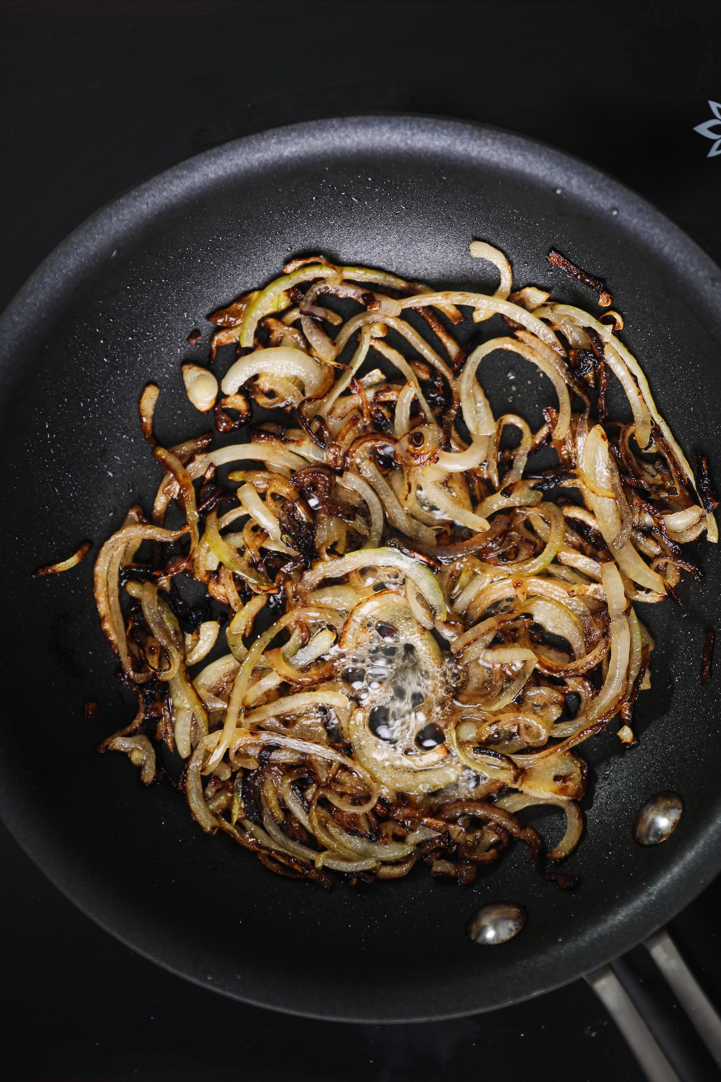 Golden fried onions slices in a frying pan with honey.