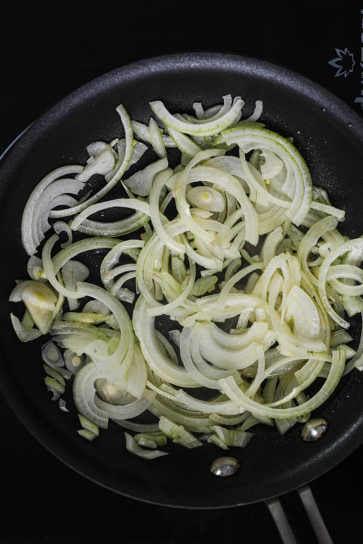 Onion slices in oil in a fry pan.