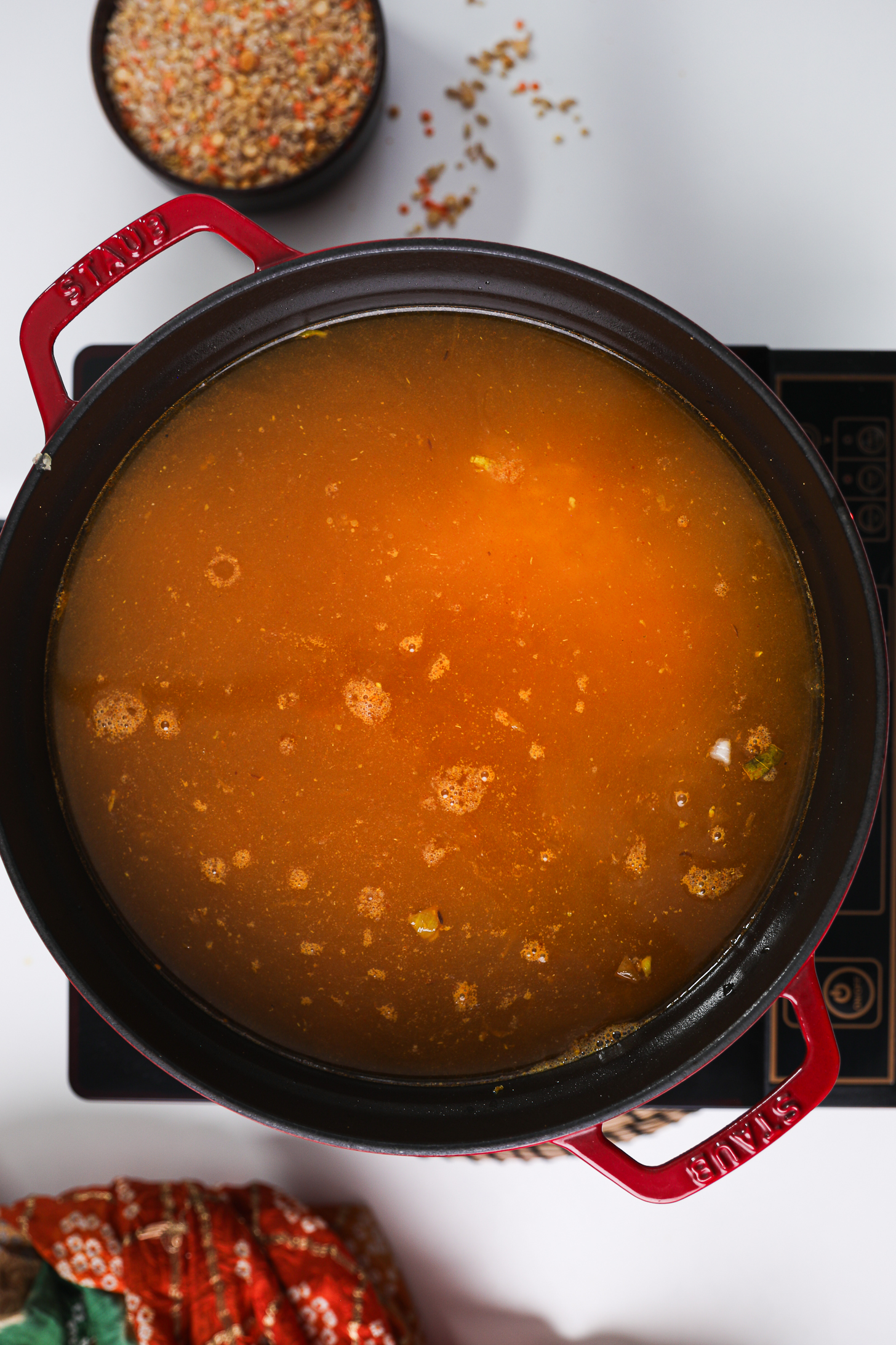 Orange-colored liquid-filled cooking pot on a mobile cooktop.