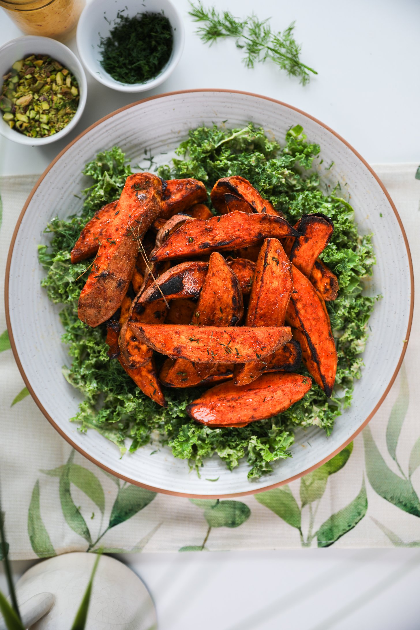 A large plate with a bed of chopped kale topped with roasted charred sweet potato wedges.