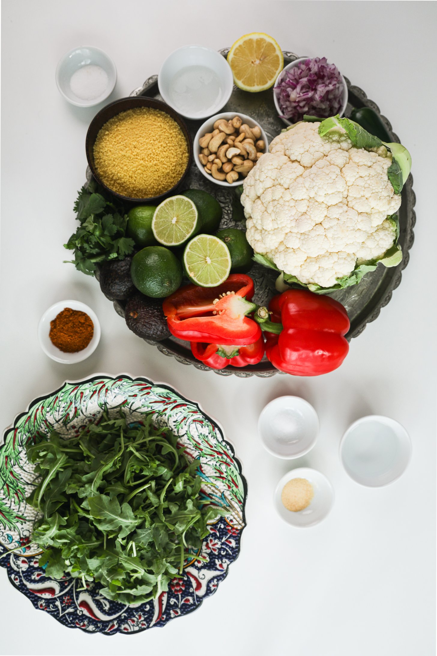 Overhead image of a food display including vegetables, arugula, spices, cashews and couscous.