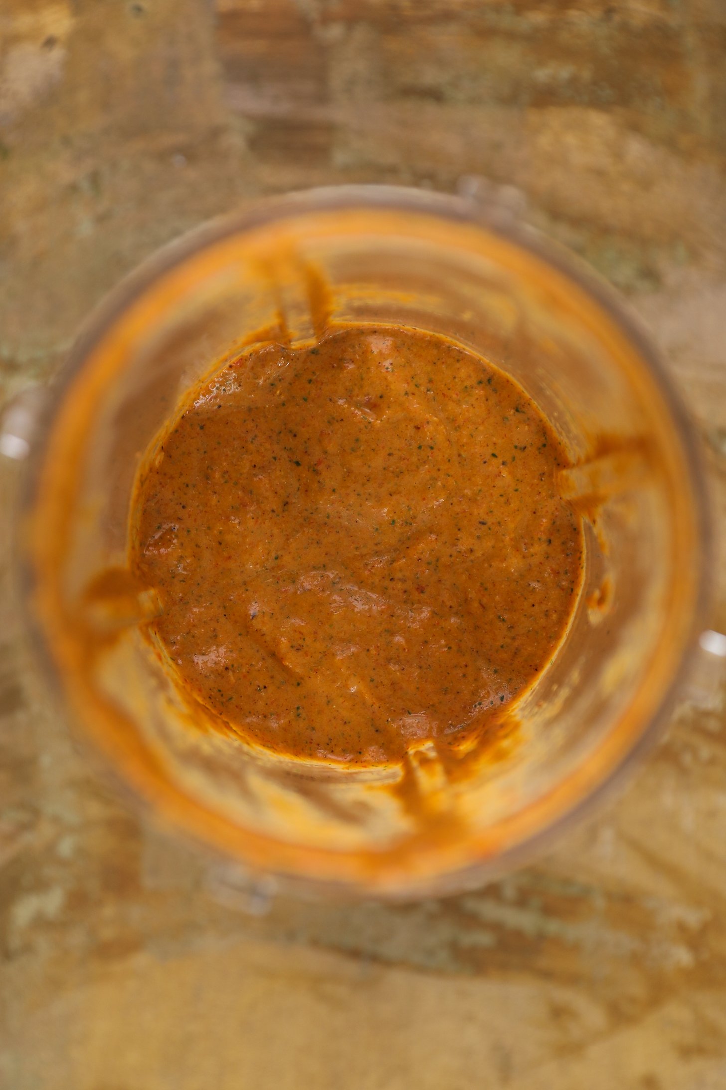 Top view of blender cup half full with a thick orange coloured marinade.