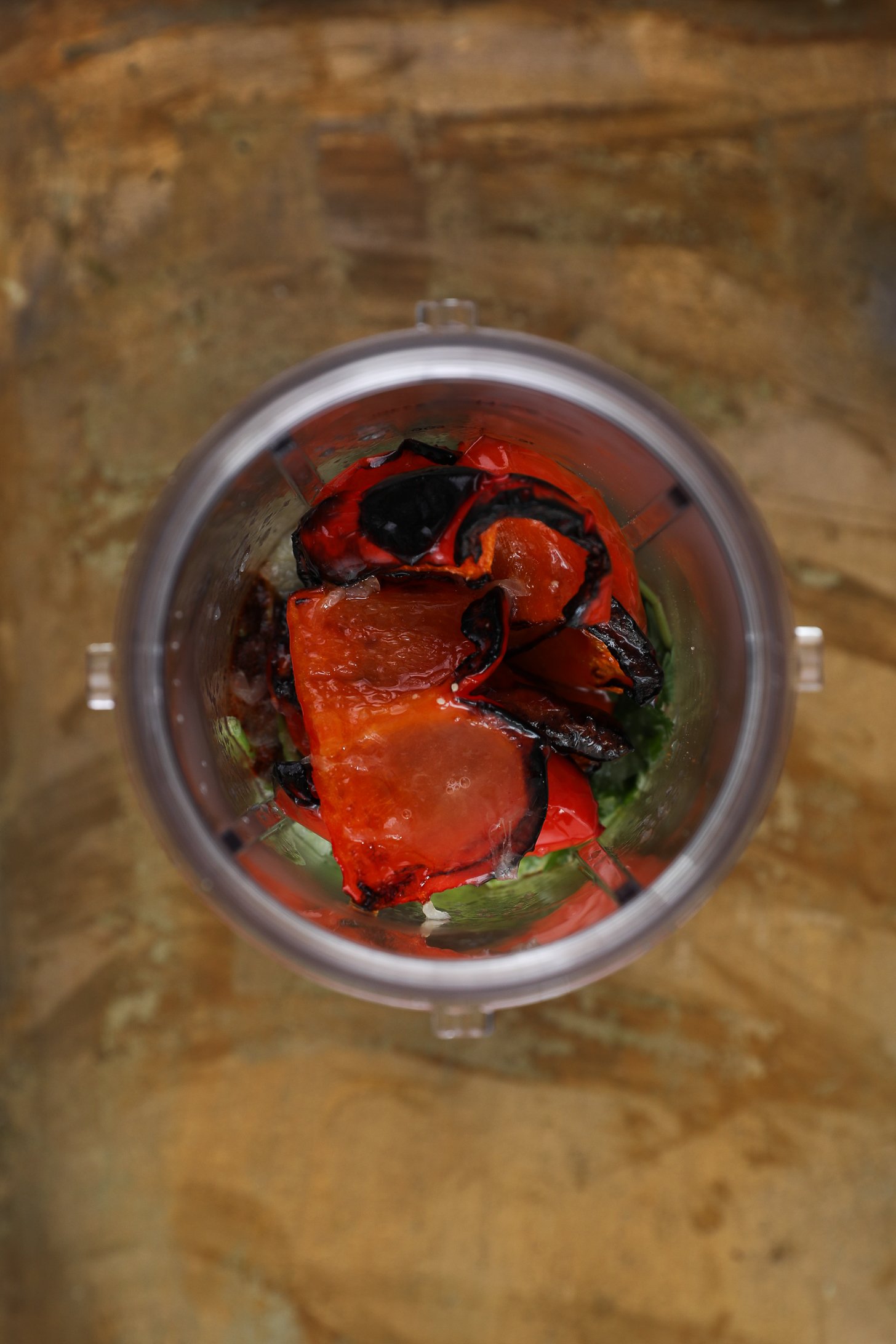 Top view of blender cup with grilled red pepper chunks.