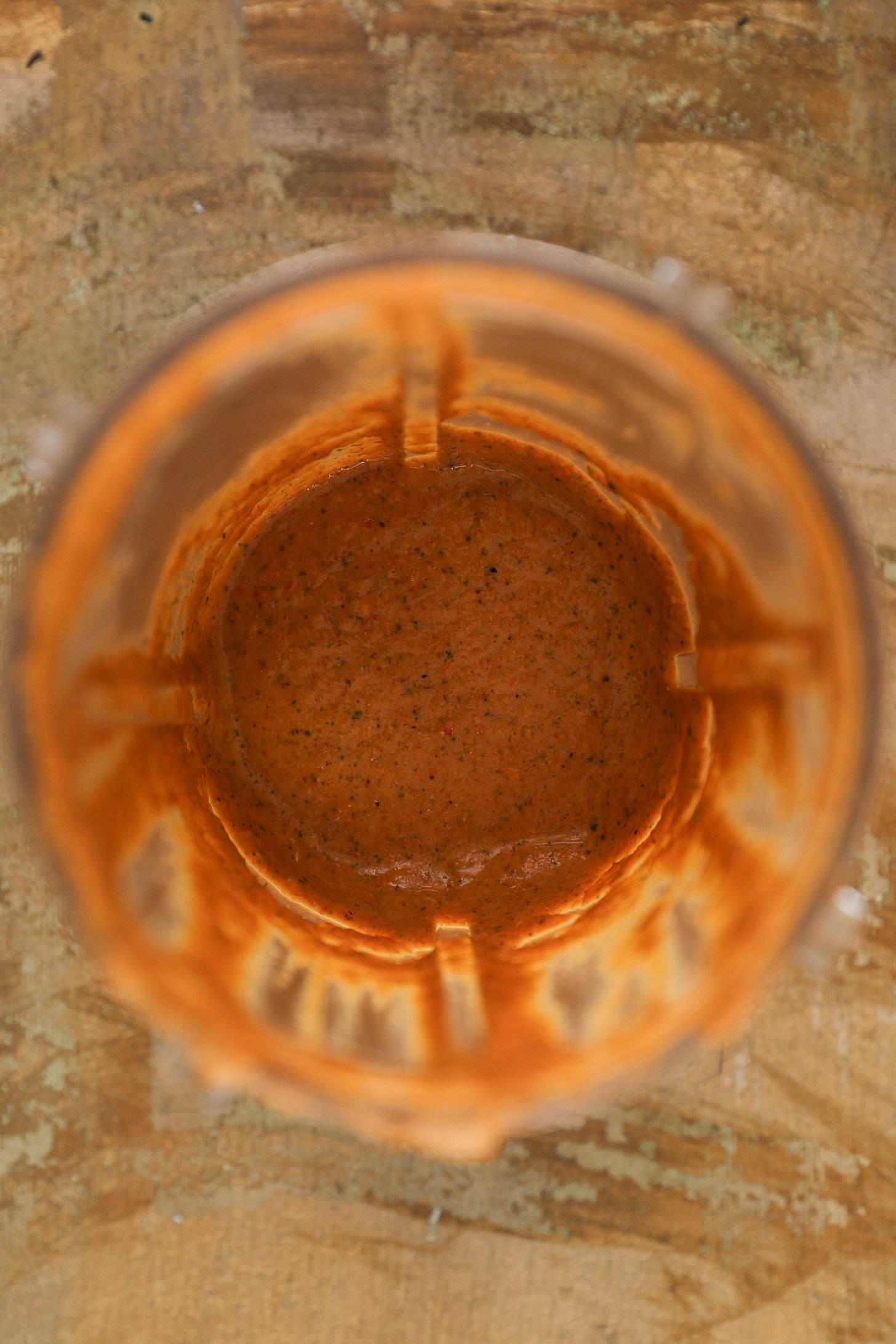 Top view of blender cup with a small quantity of a thick orange coloured marinade.