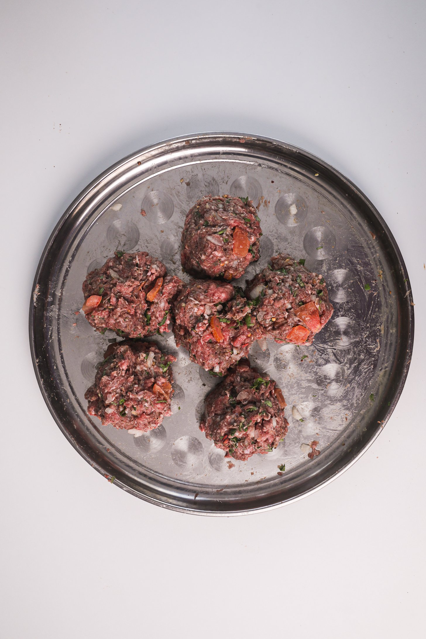 Six raw Chapli Kebab balls on a tray.