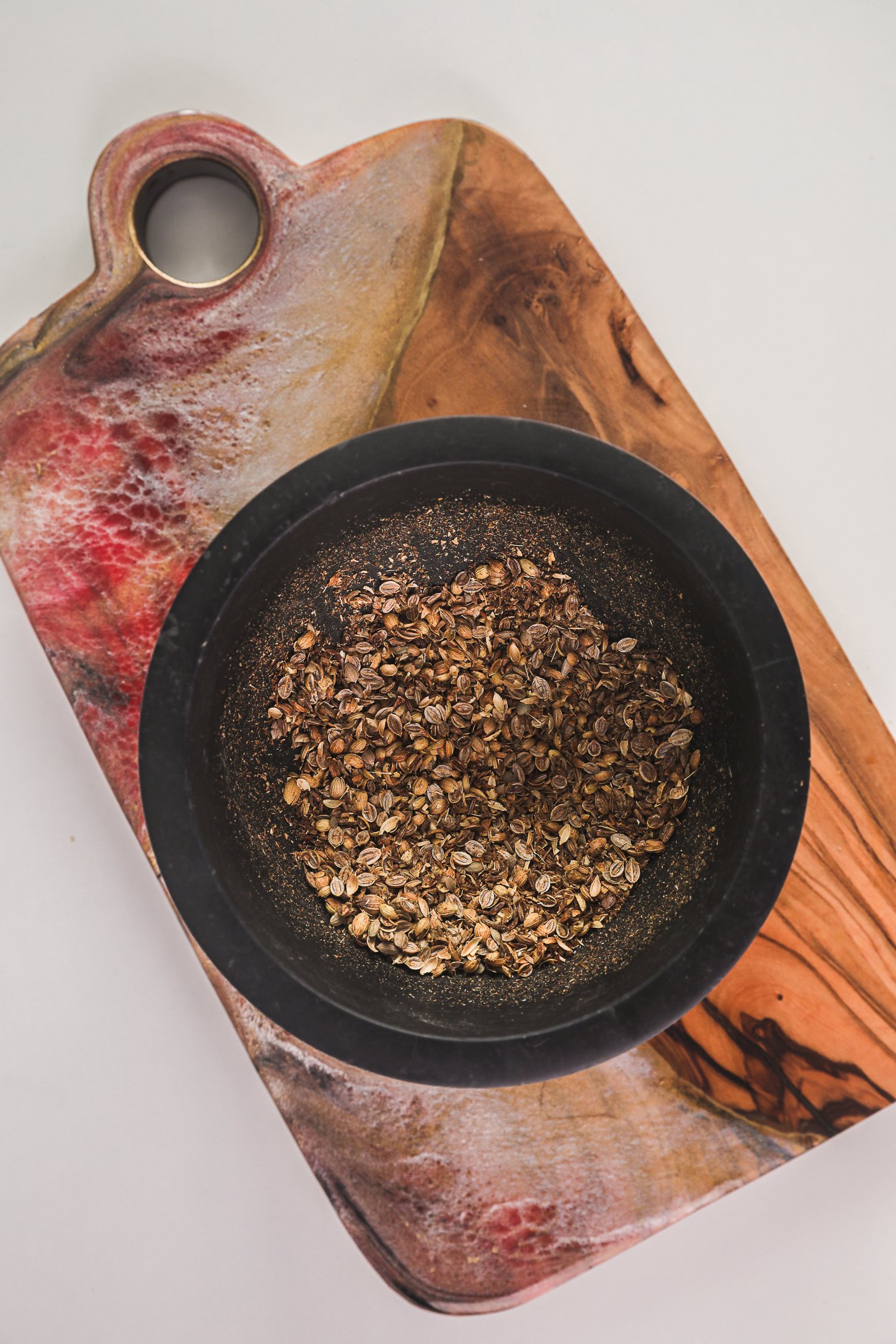 Crushed cumin and coriander seeds in a pestle and mortar.